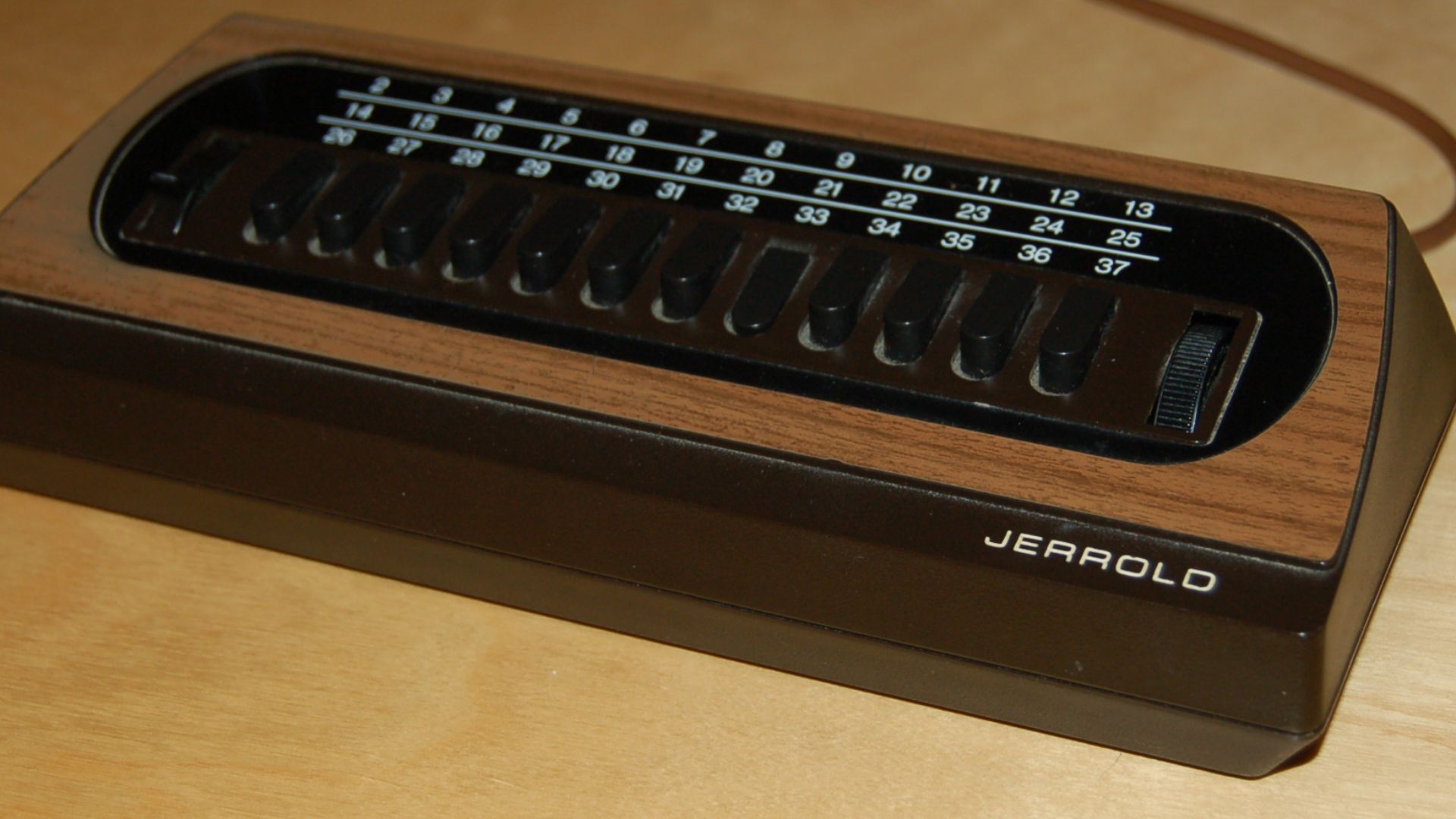 A 1970s era Jerrold brand cable box. Channels are selected by a combination of a three-position switch, and one of 12 selective push buttons. A fine tuning knob is at the right.