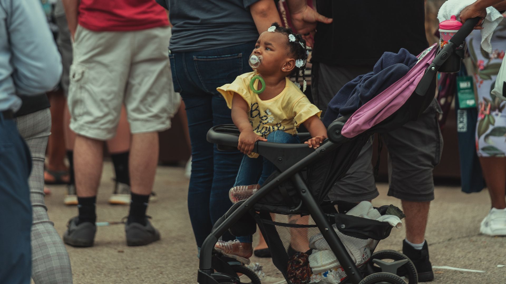 A diverse crowd in a vibrant urban setting featuring a child in a stroller.