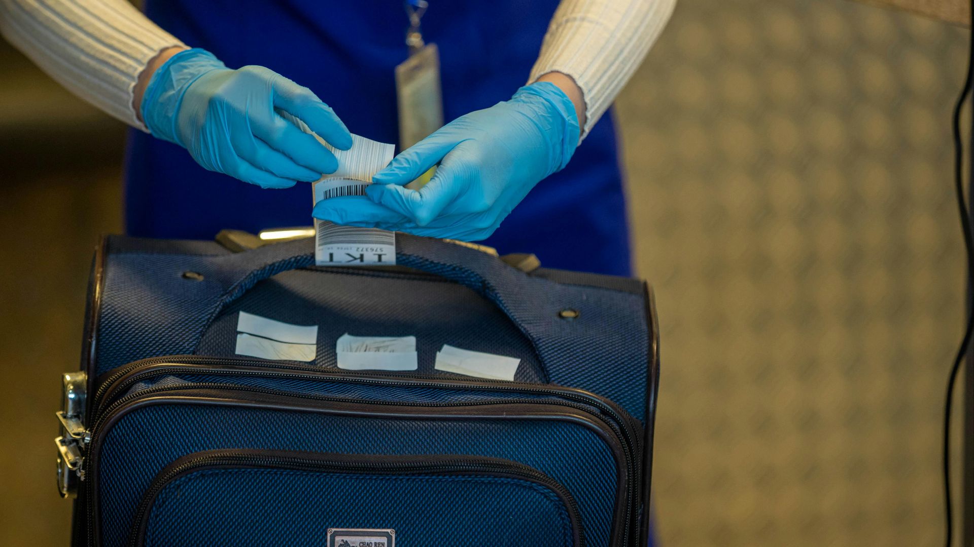 Close-up of airport security process with gloved hands inspecting luggage tags.