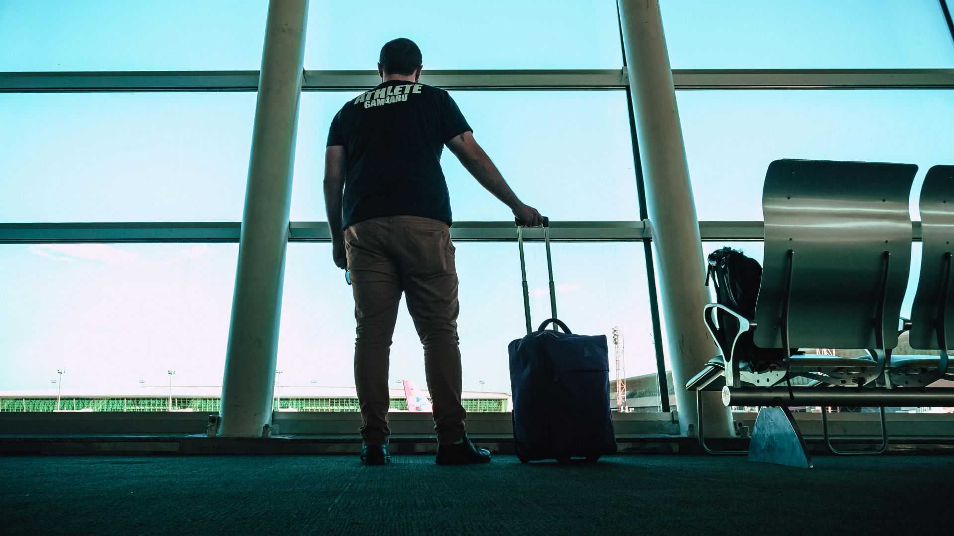 Man with luggage waiting at airport lounge, anticipating departure in a modern setting.