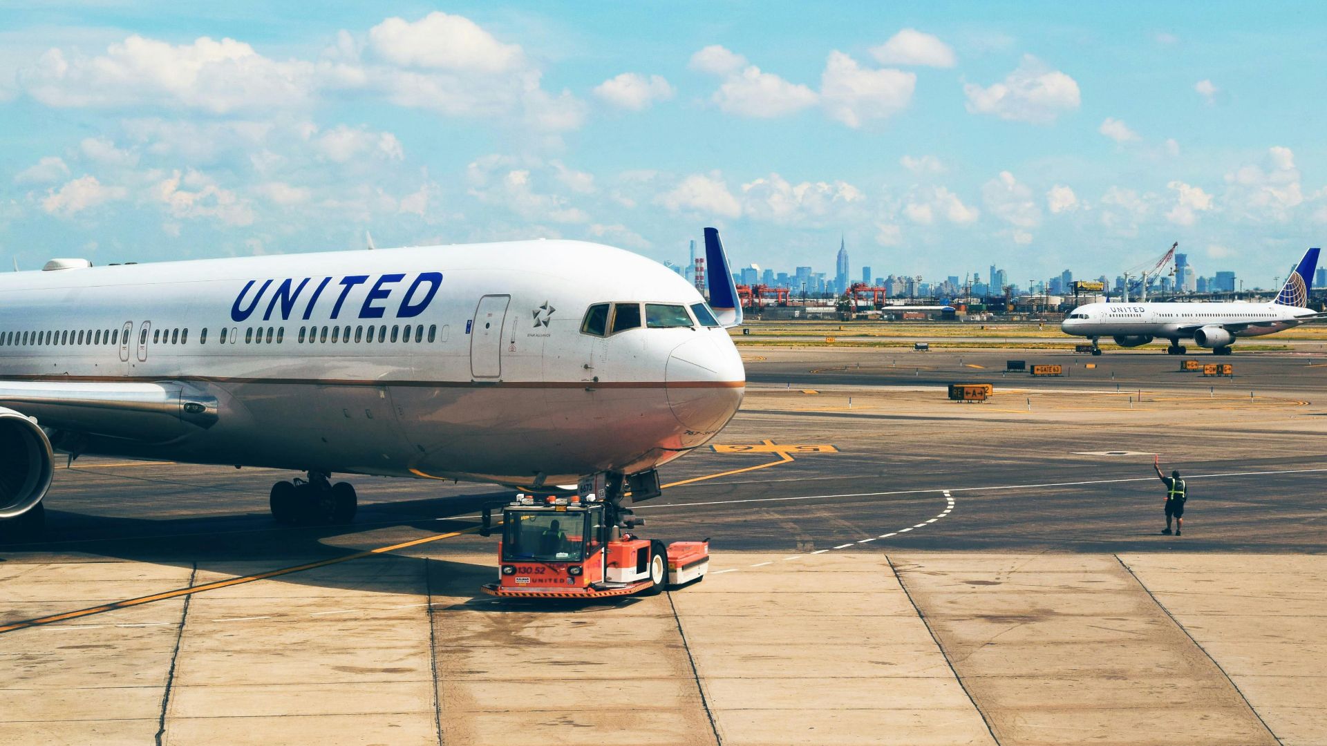 Aircraft on the runway at Newark Airport with city skyline in the background.