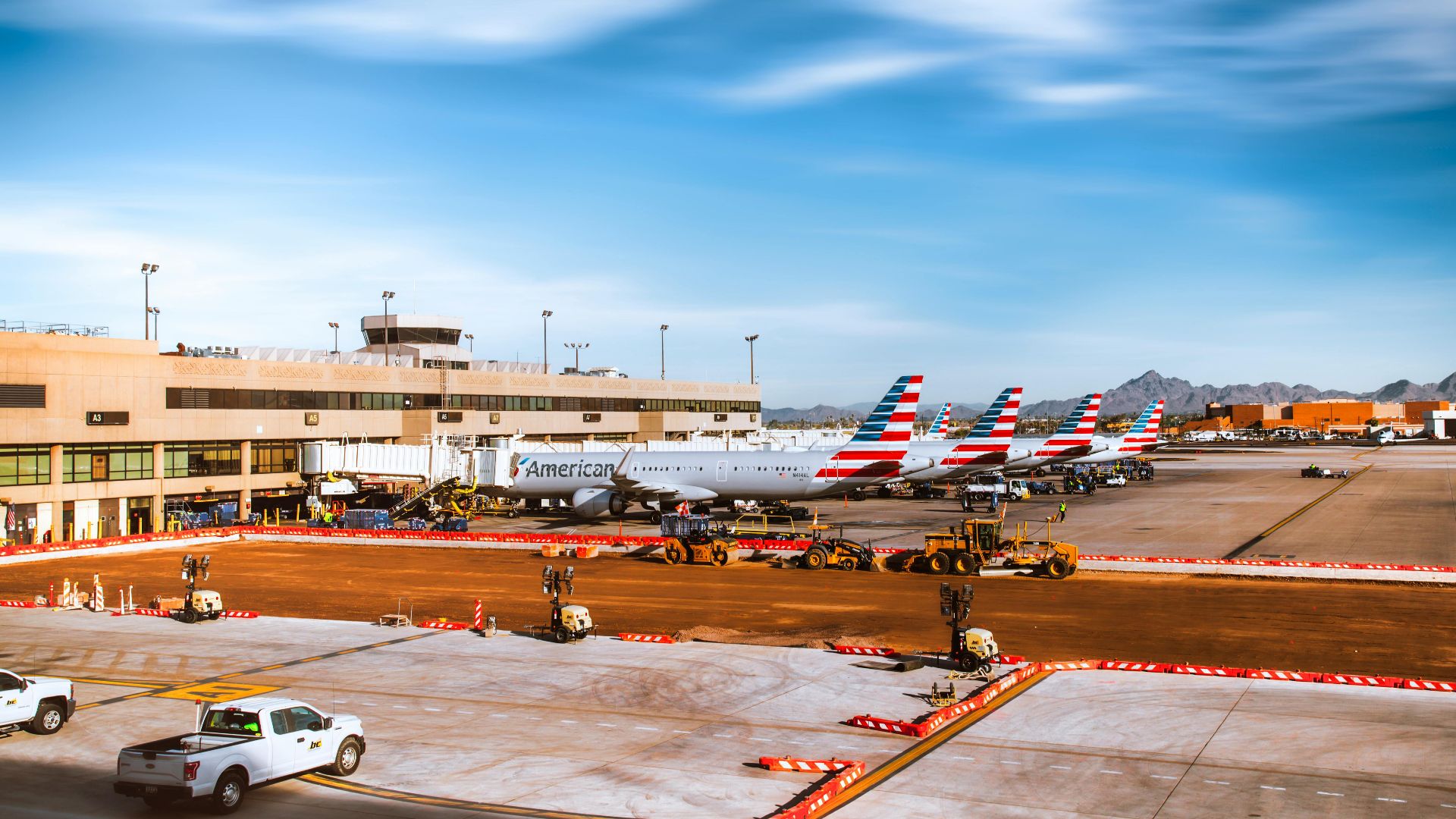 Line of American Airlines planes at Phoenix Sky Harbor with mountains in background.
