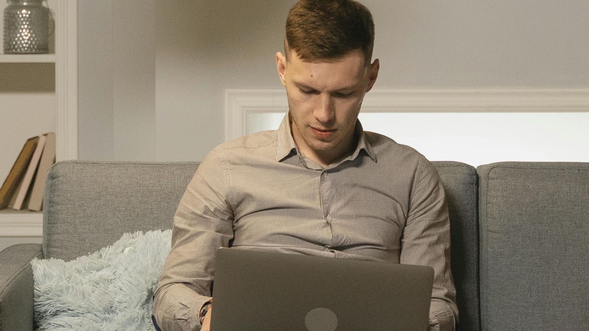 A couple relaxing in a modern living room, reading and using a laptop on the couch.