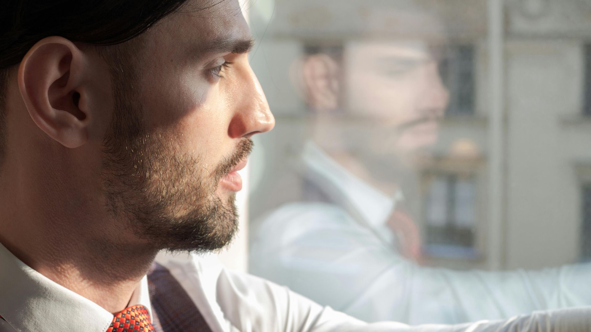 Profile of a businessman gazing through the window, contemplating his next move.