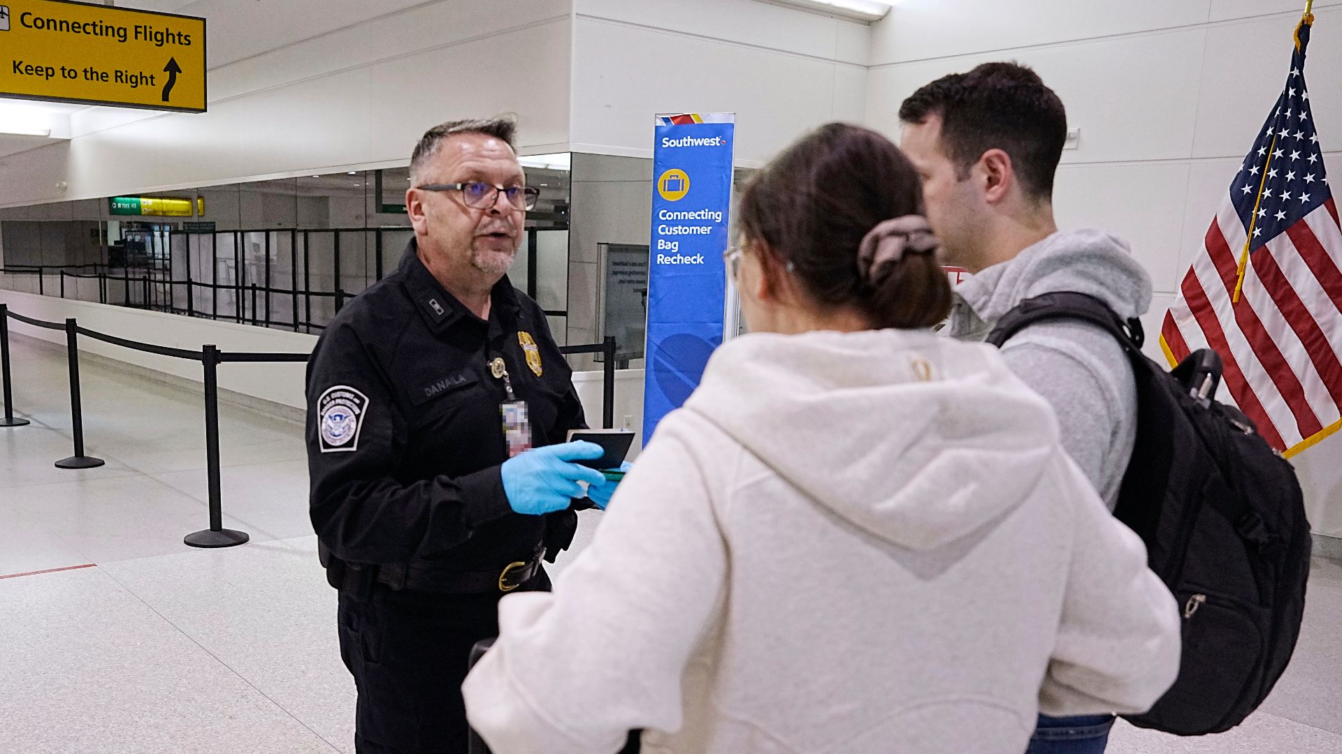 A U.S. Customs and Border Protection Office of Field Operations agriculture specialist directs  travelers arriving from an international flight towards further screening for agricultural products at Baltimore/Washington International Thurgood Marshall Air