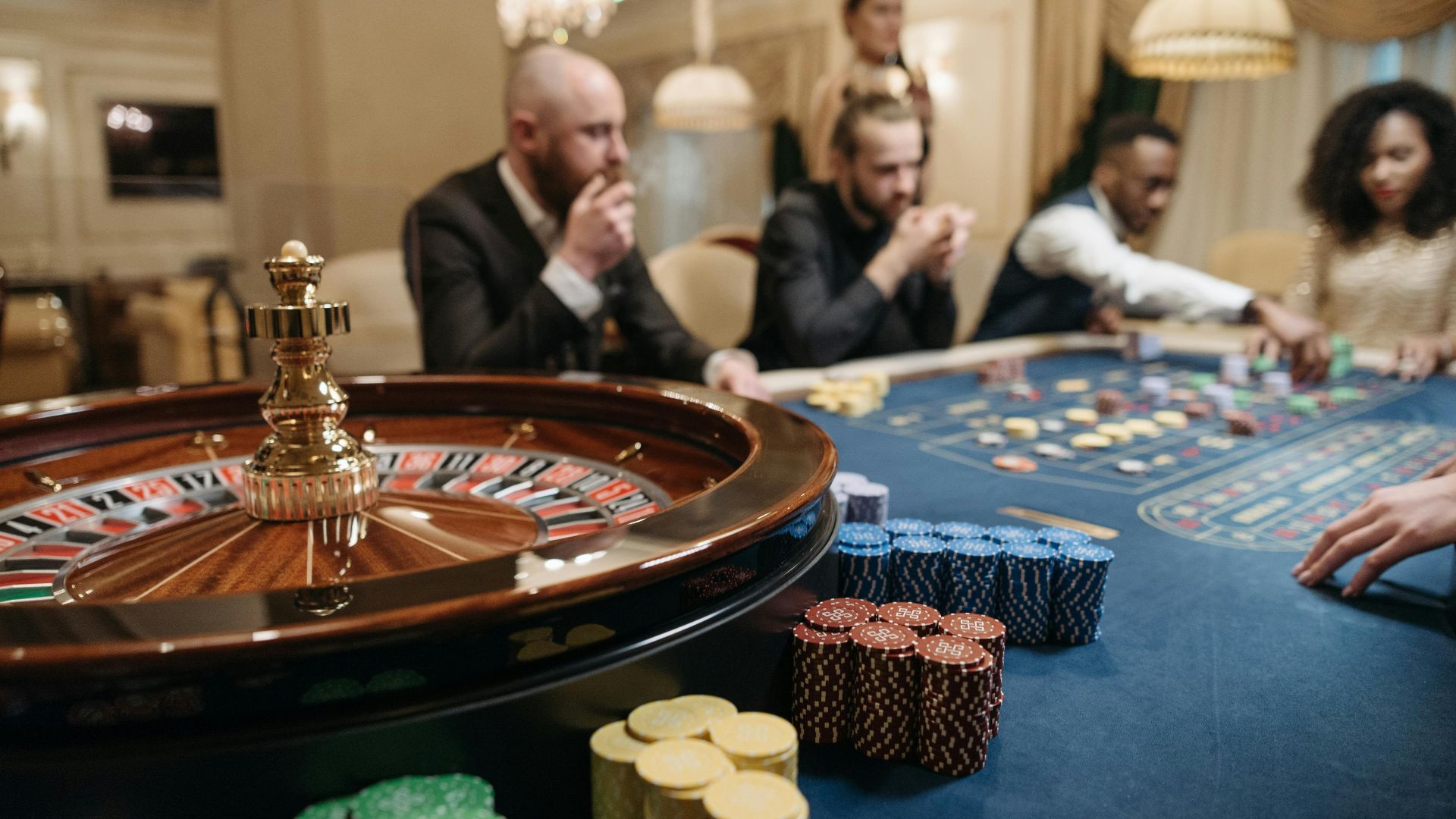 People enjoying a roulette game in an upscale casino setting with chips and a roulette wheel.
