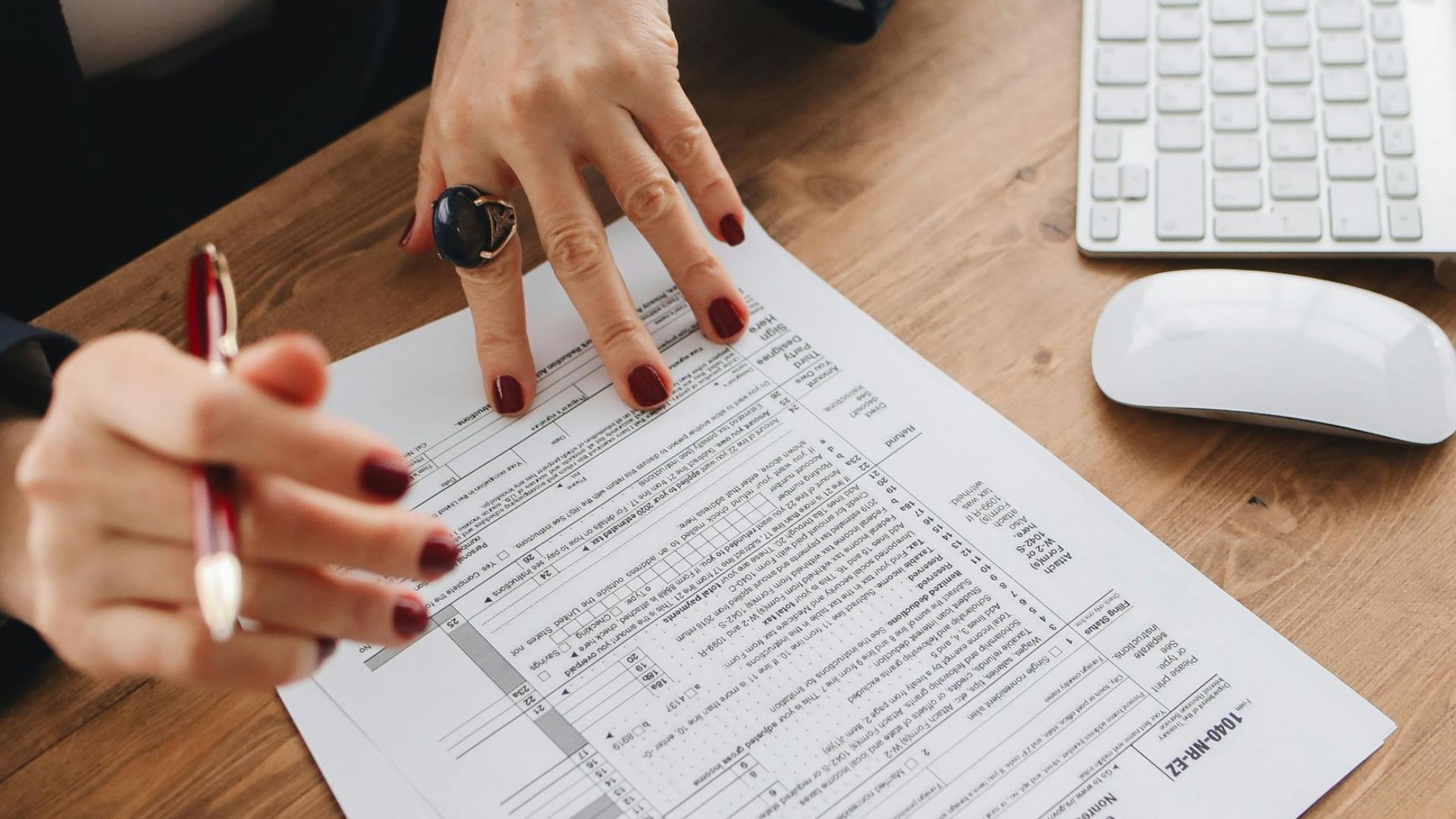 Close-up of a professional examining tax documents on a wooden desk indoors.