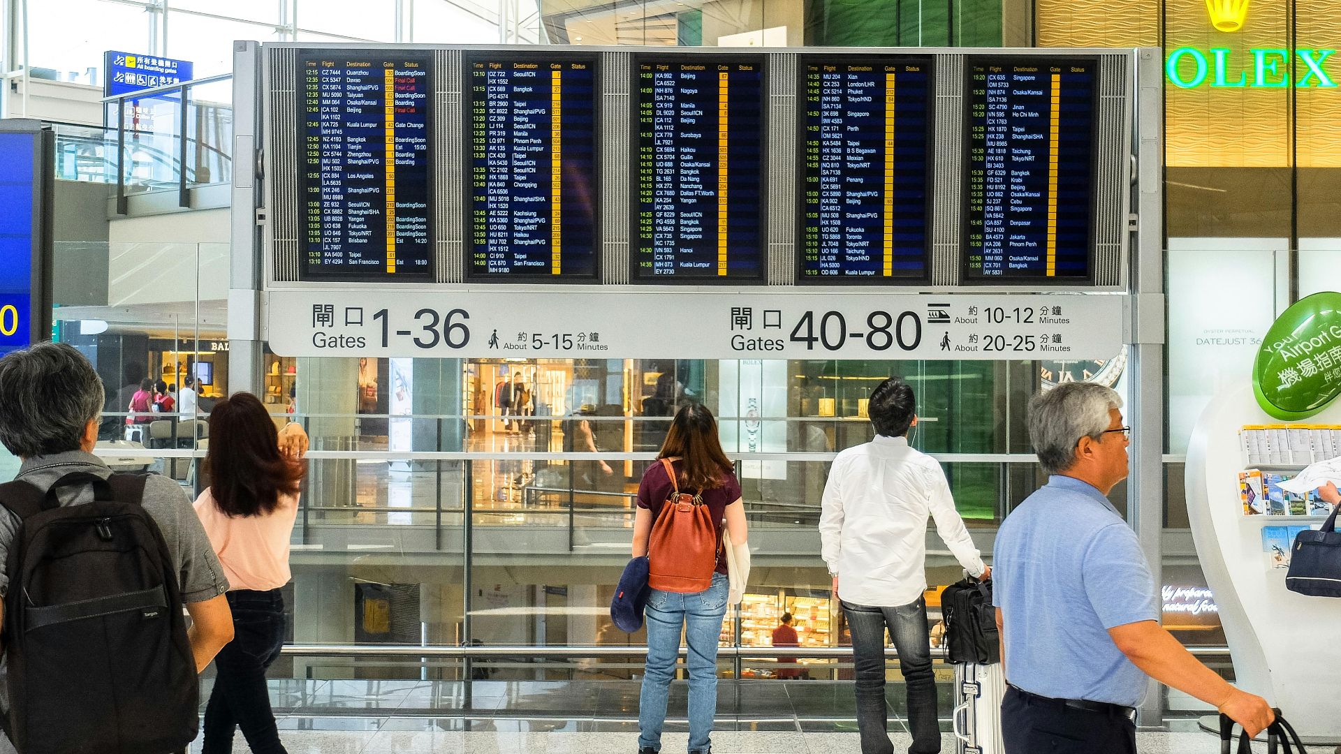 Passengers checking the departure board at Hong Kong International Airport terminal.