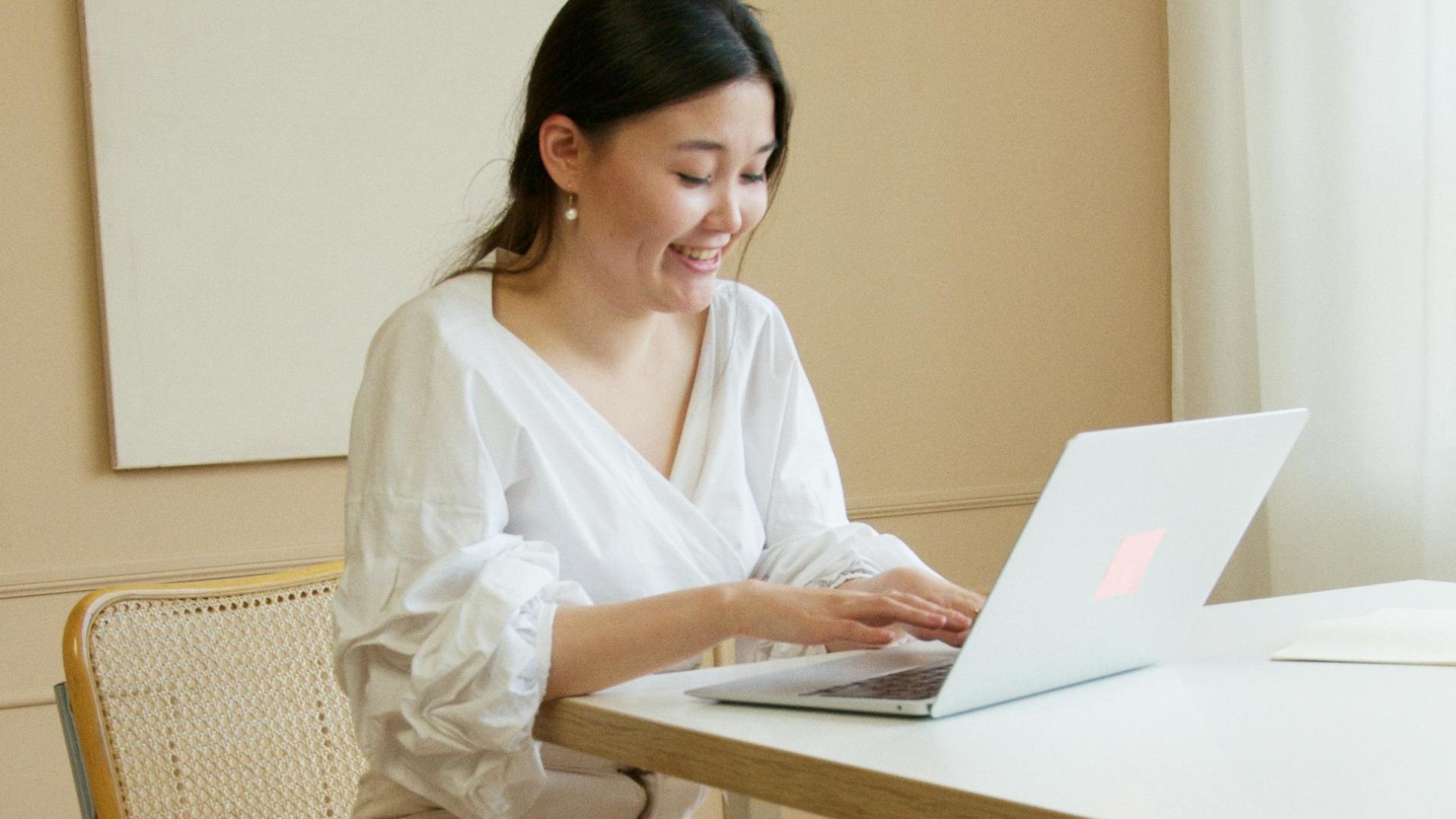 A woman professionally dressed, working on a laptop in a modern office, conveying productivity and modern work culture.