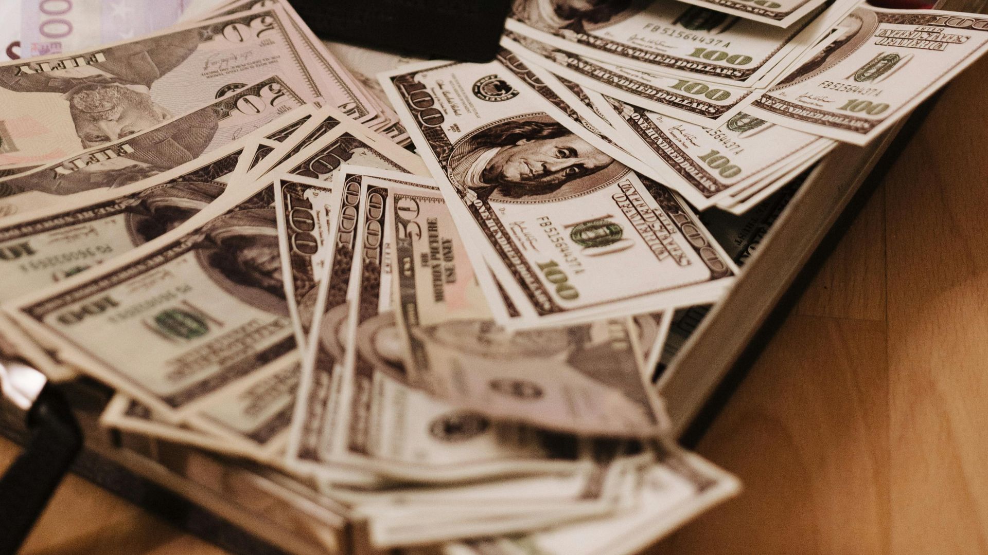 Open suitcase filled with cash, gold necklaces, and a sale tag, symbolizing wealth.