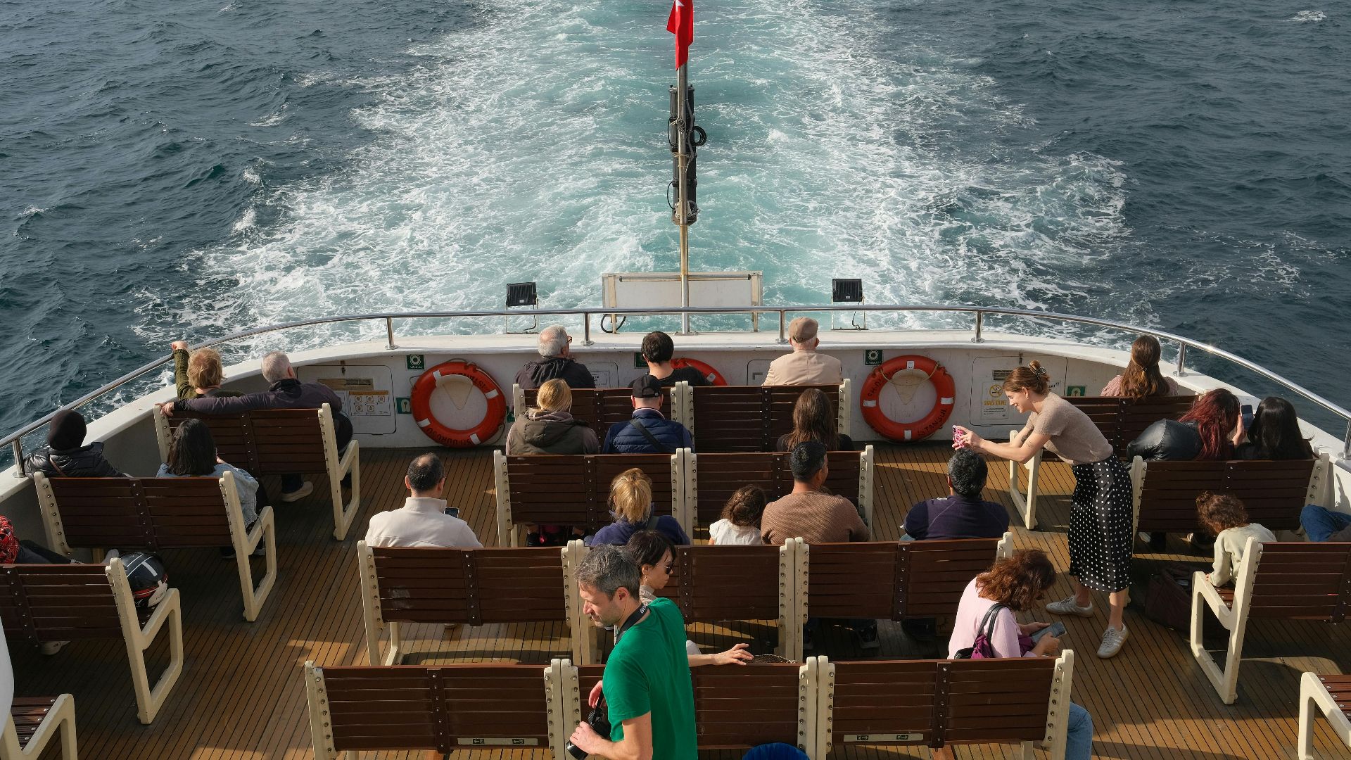A diverse group of people enjoy a sunlit boat ride, showcasing movement and leisure.