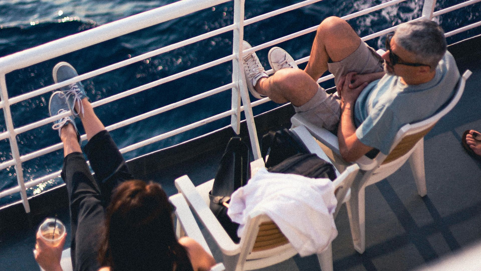 Couple relaxing on a cruise ship deck, enjoying the serene ocean view on a sunny day.
