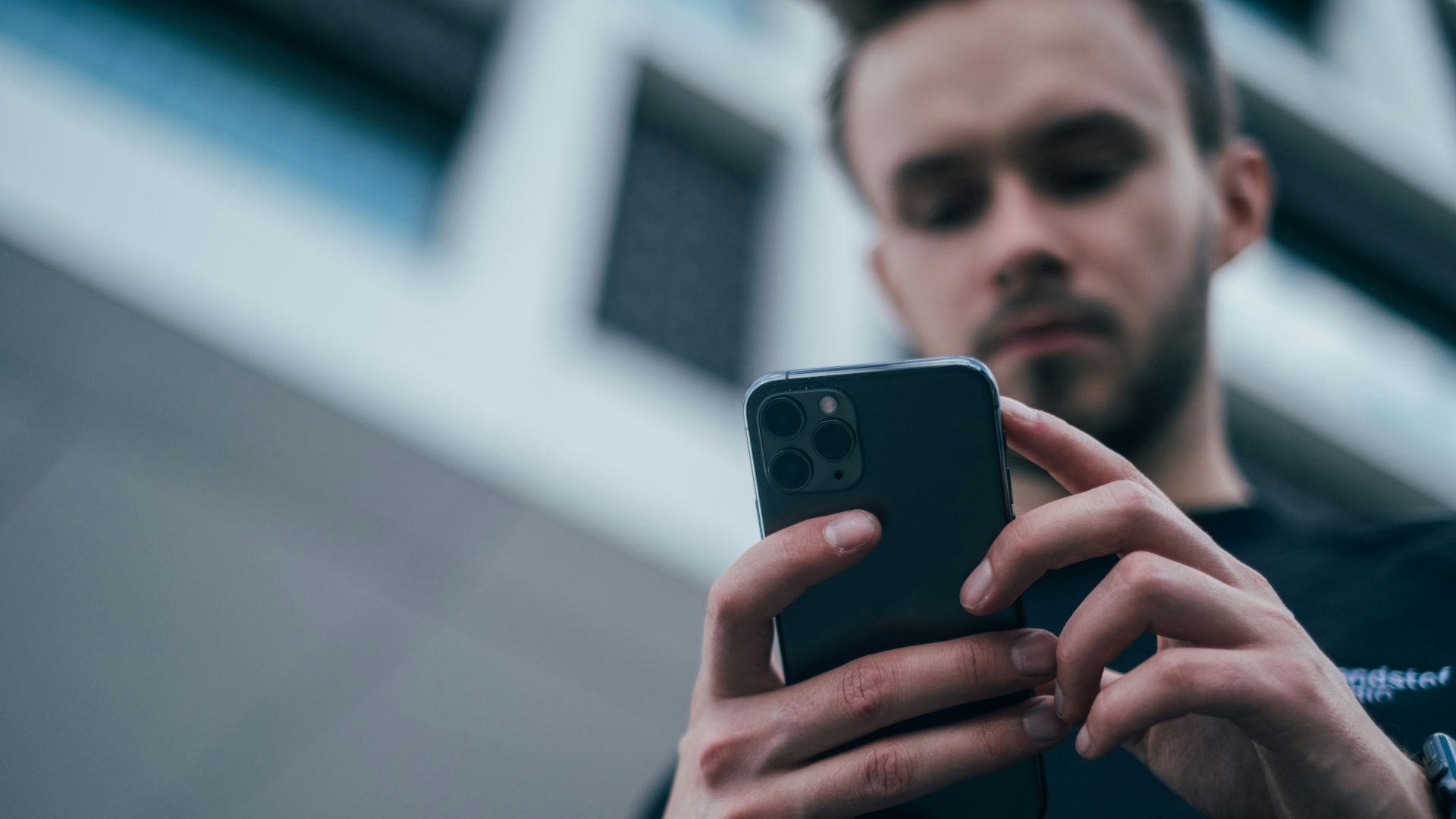 man wearing black sweater using smartphone