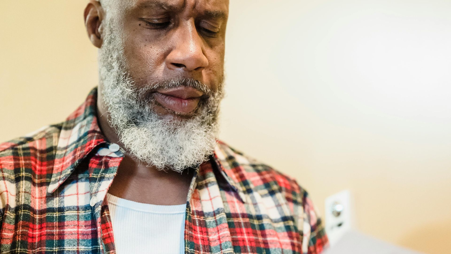 A mature man with a beard attentively reading documents indoors in a focused manner.