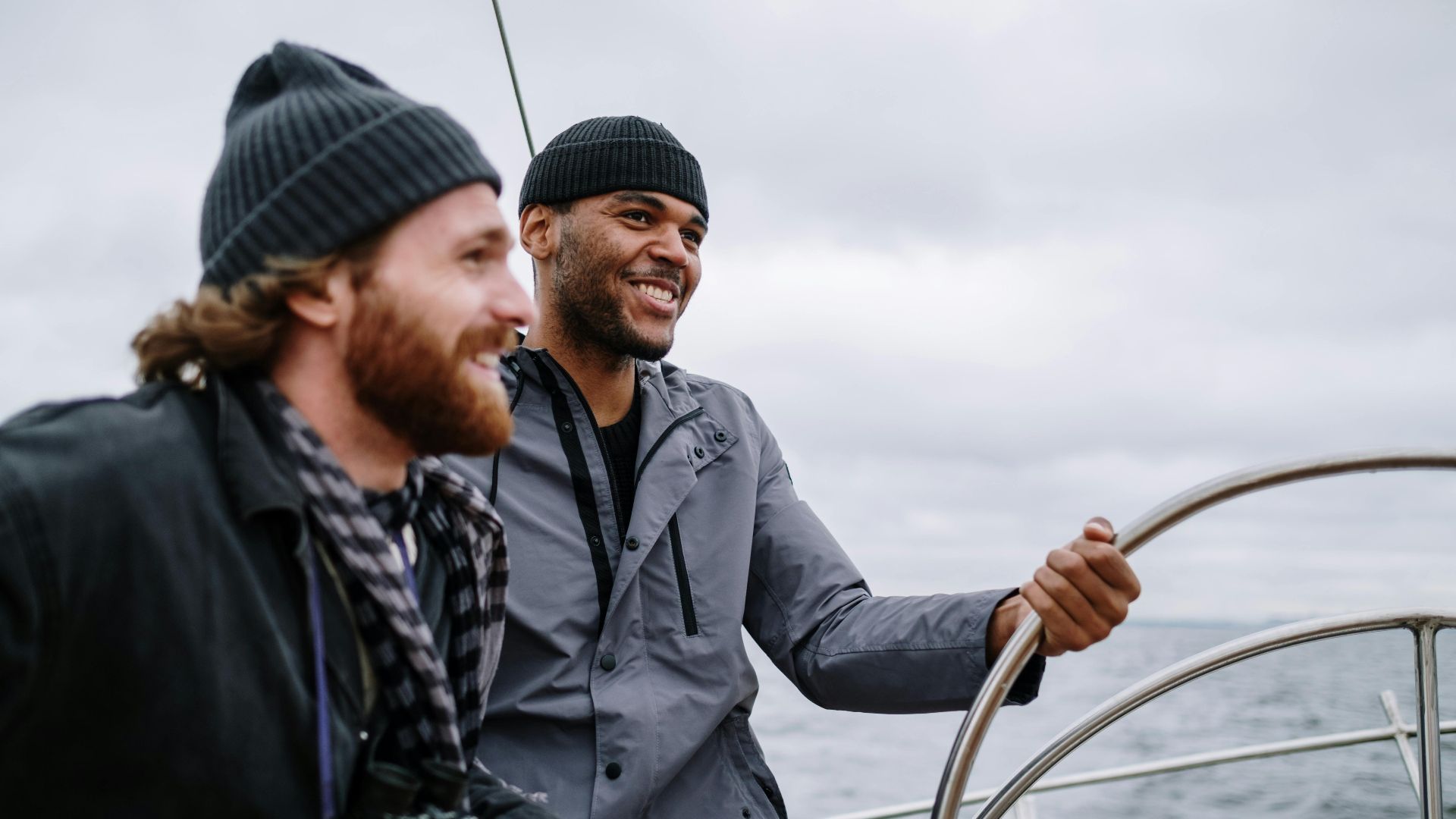 Two friends laugh and sail on a boat, embracing freedom and adventure on the open sea.