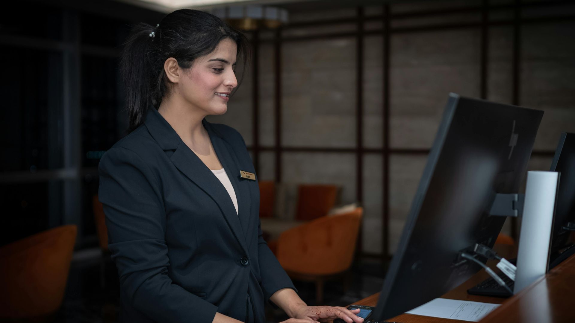 A female receptionist working at a hotel front desk in Islamabad, Pakistan.