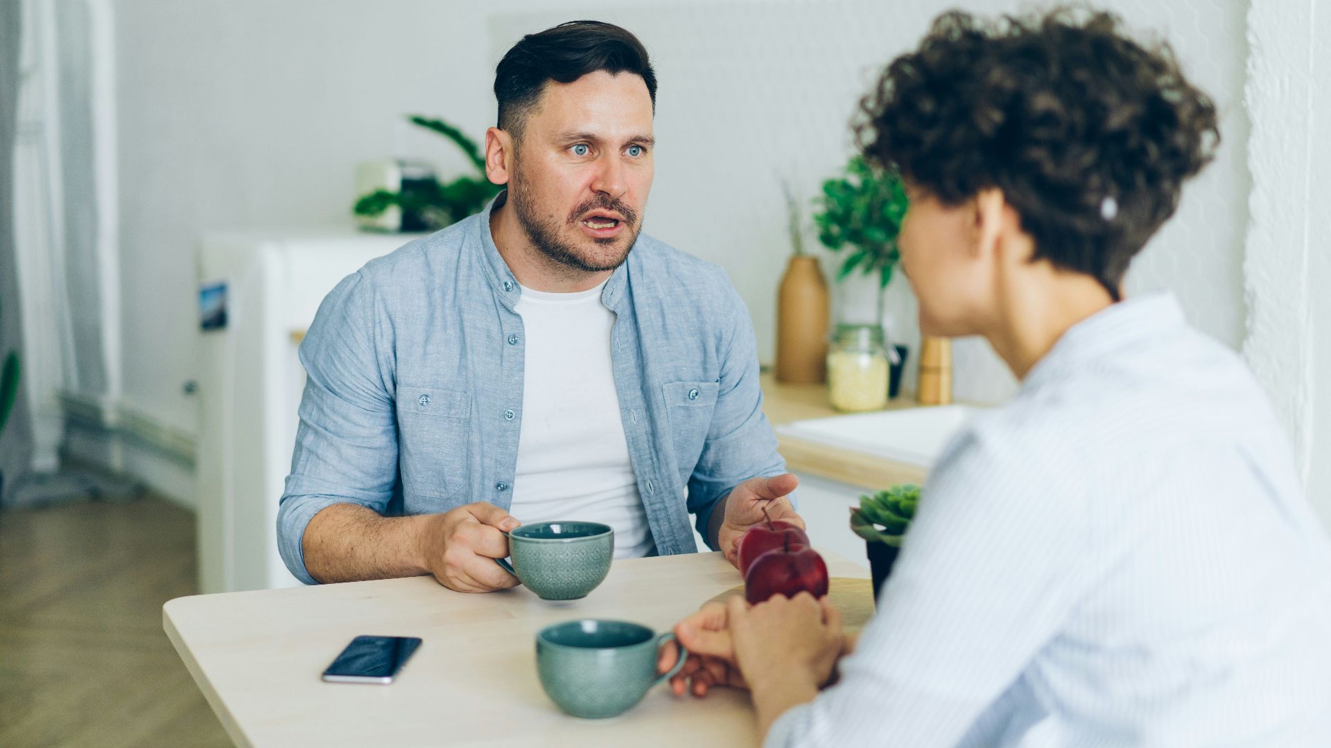 a man sitting at a table talking to a woman