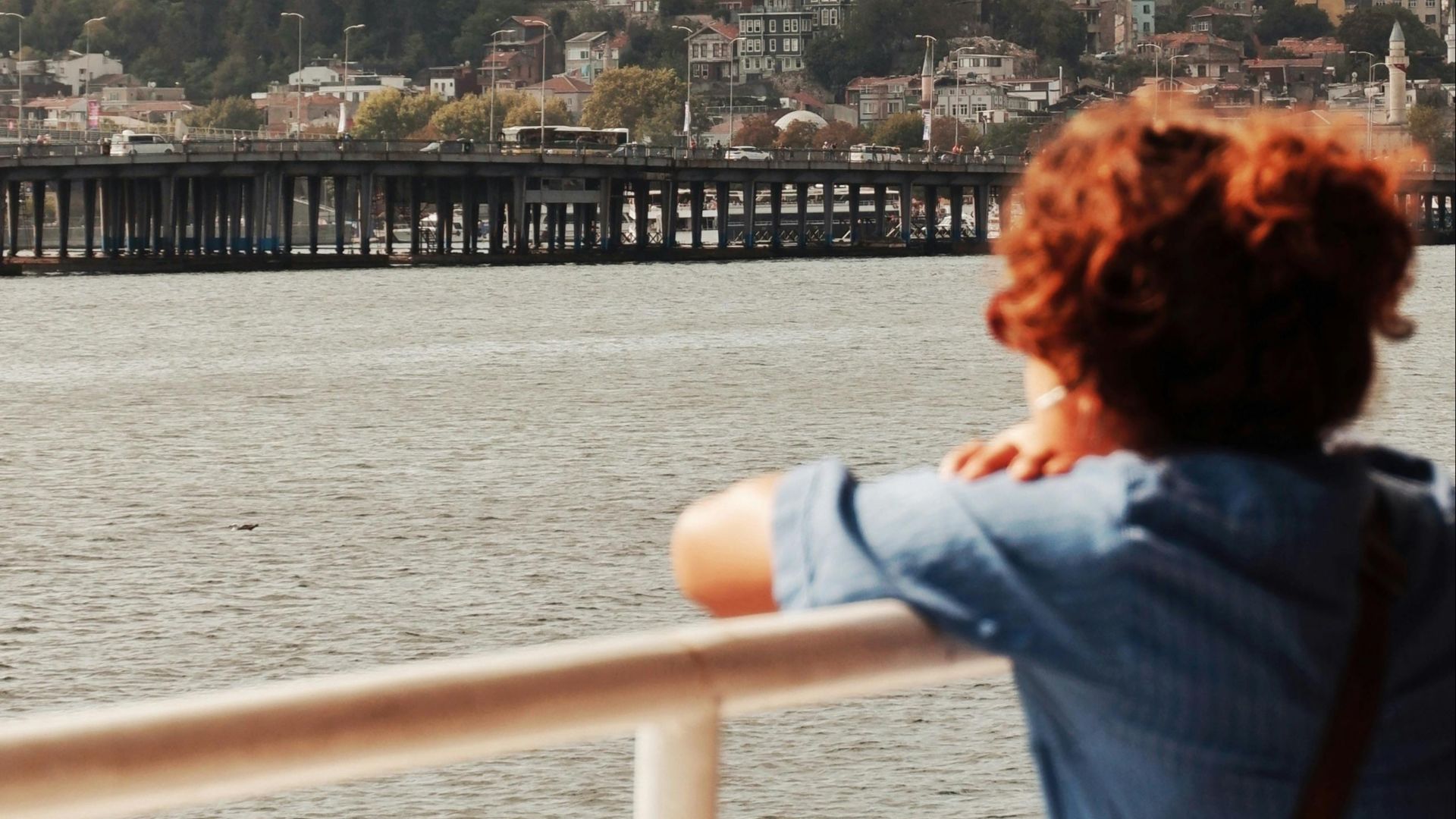 A woman views Istanbul's skyline from a ferry, featuring the Hagia Sophia.