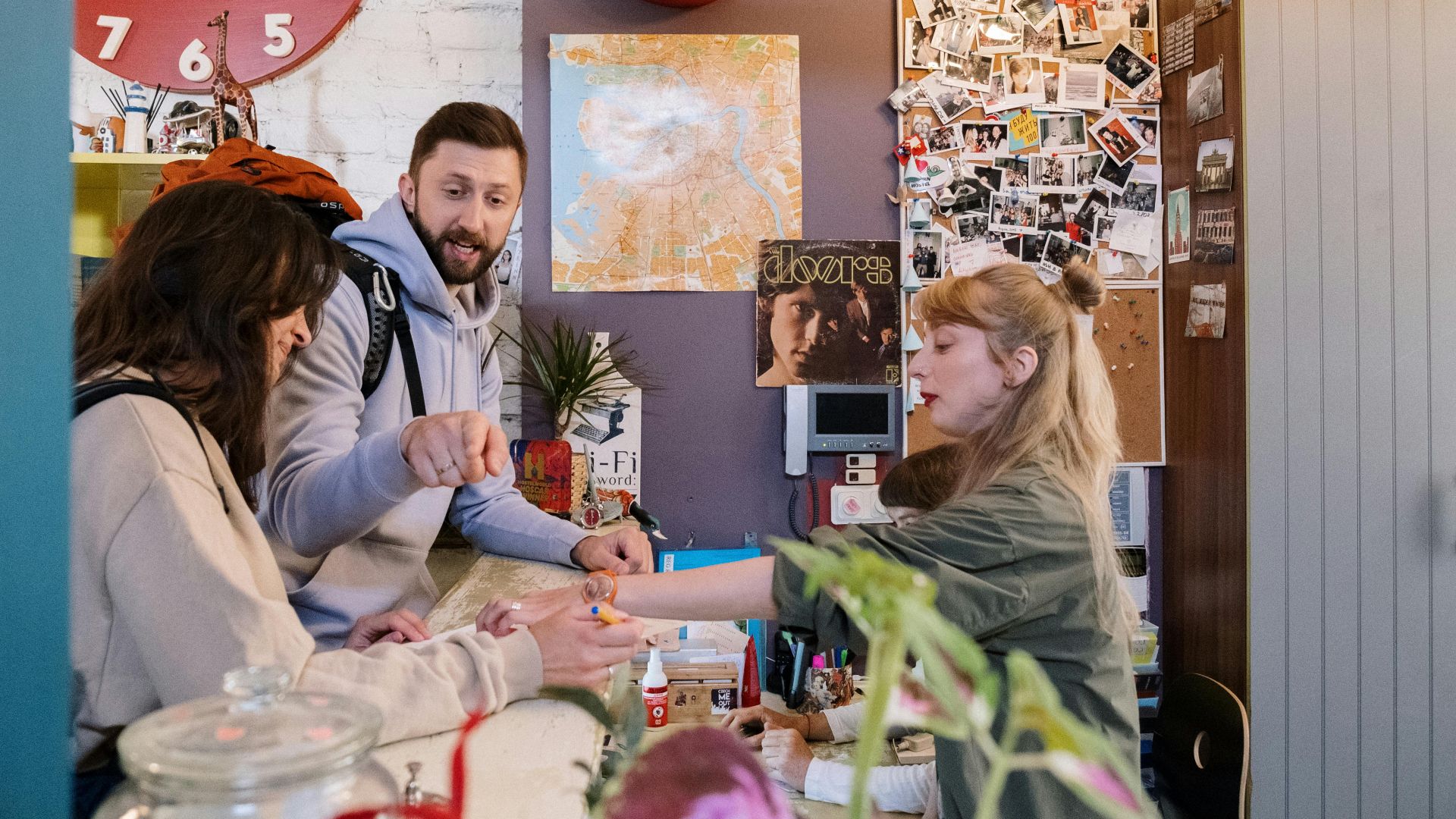 Guests checking in at a hostel reception with a warm interaction between a couple and staff.