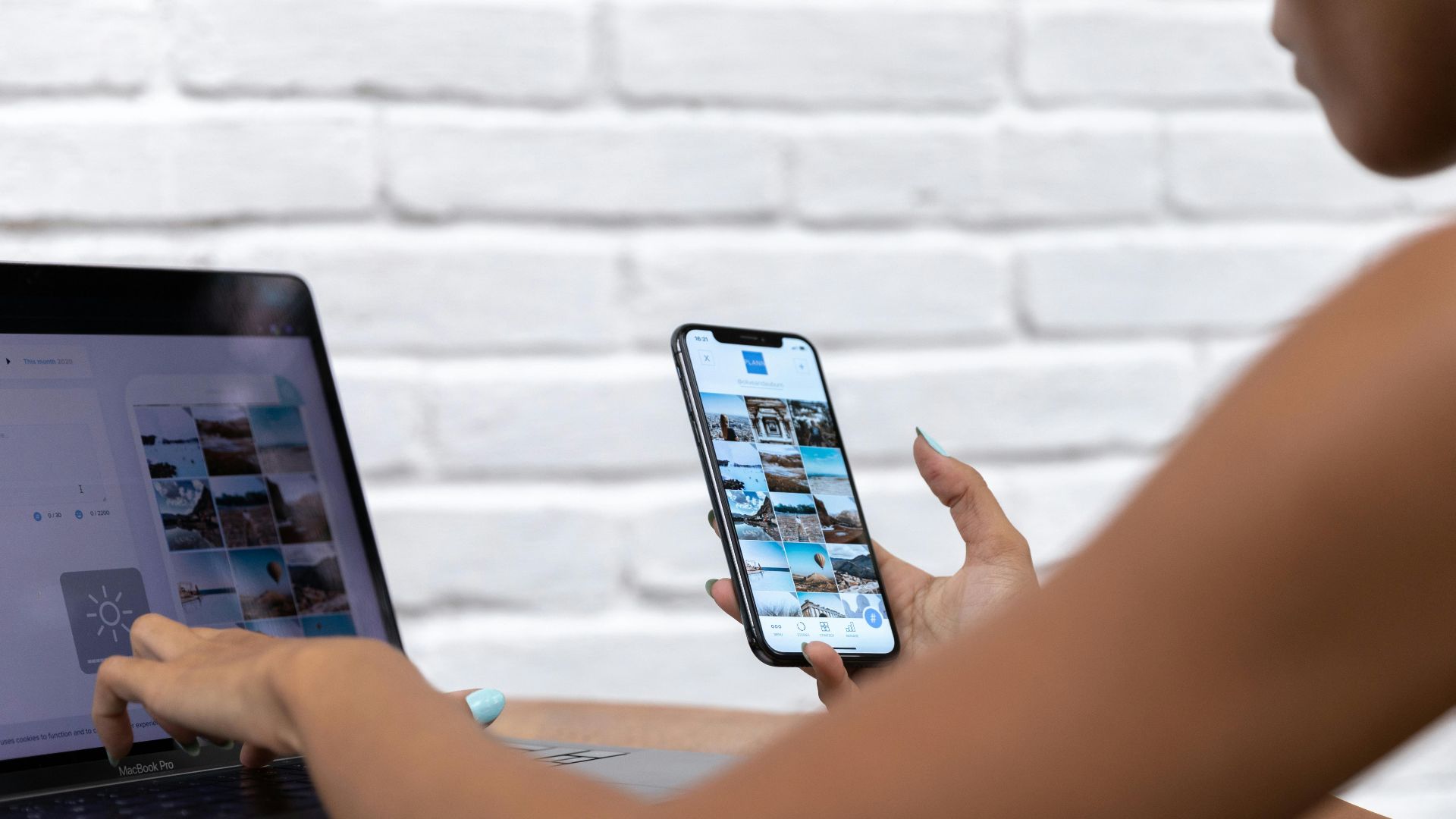 A woman working remotely using a laptop and smartphone, focusing on social media content.