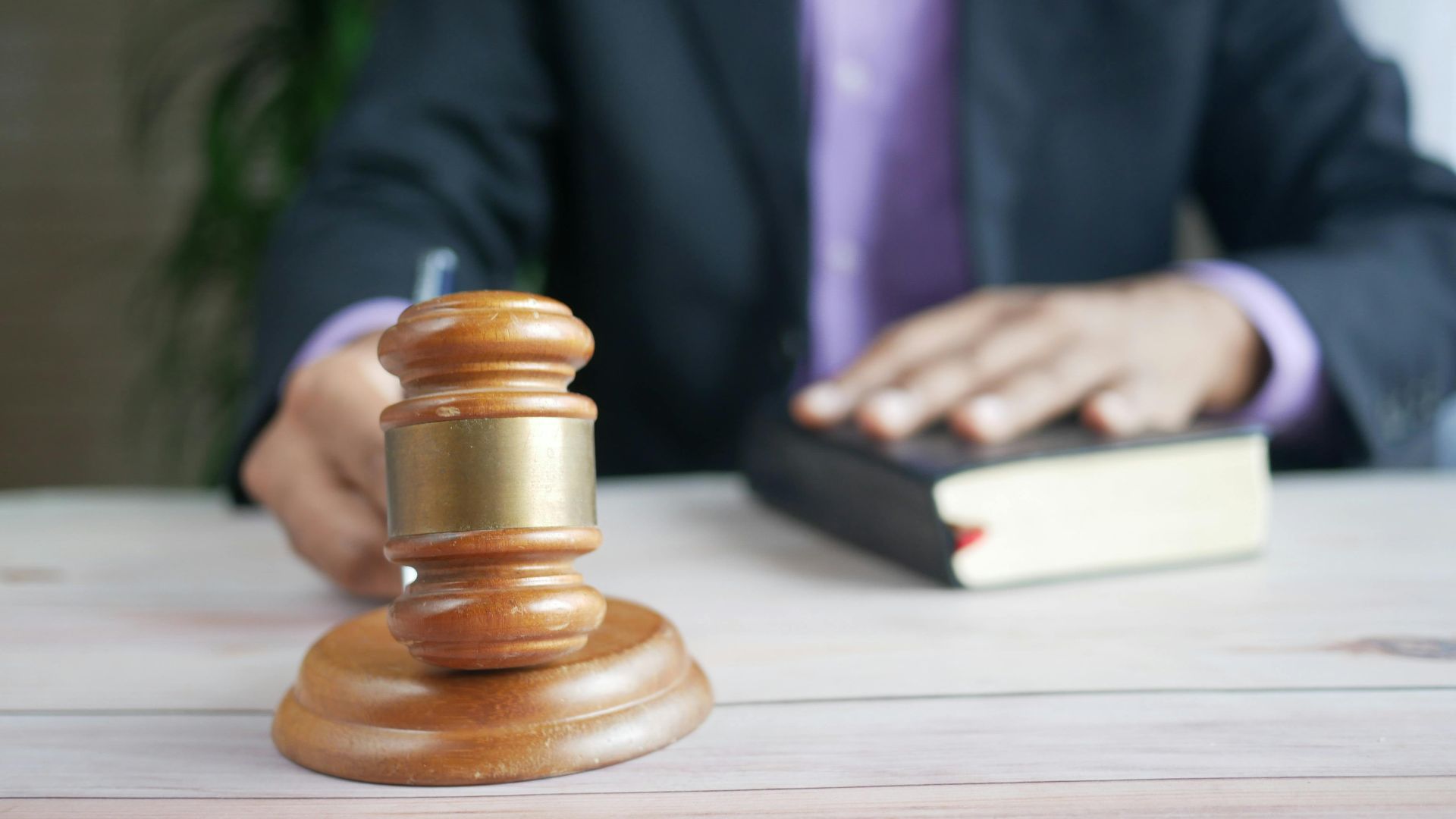 A wooden gavel and legal book represent justice in a court setting, emphasizing order and legal authority.