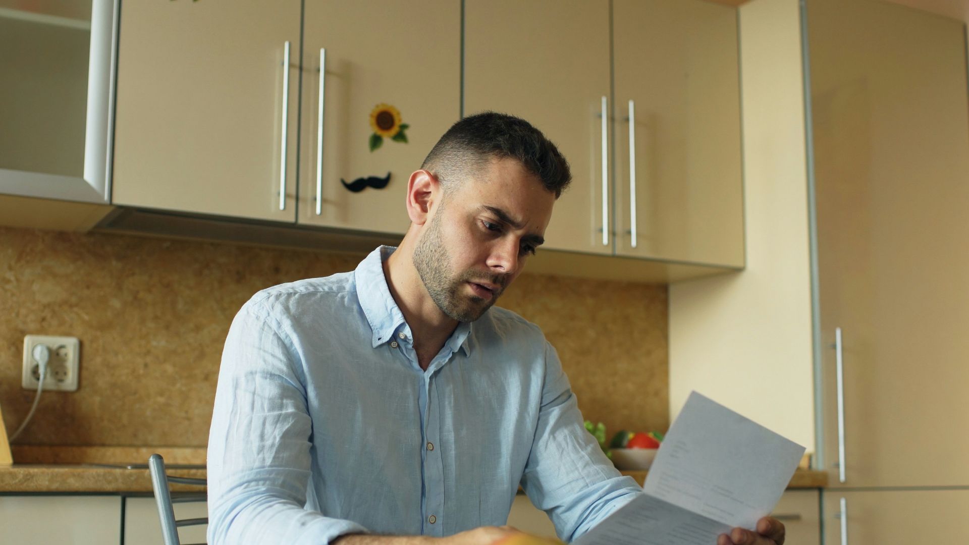 Man reading document at kitchen table with fruit and fruit
