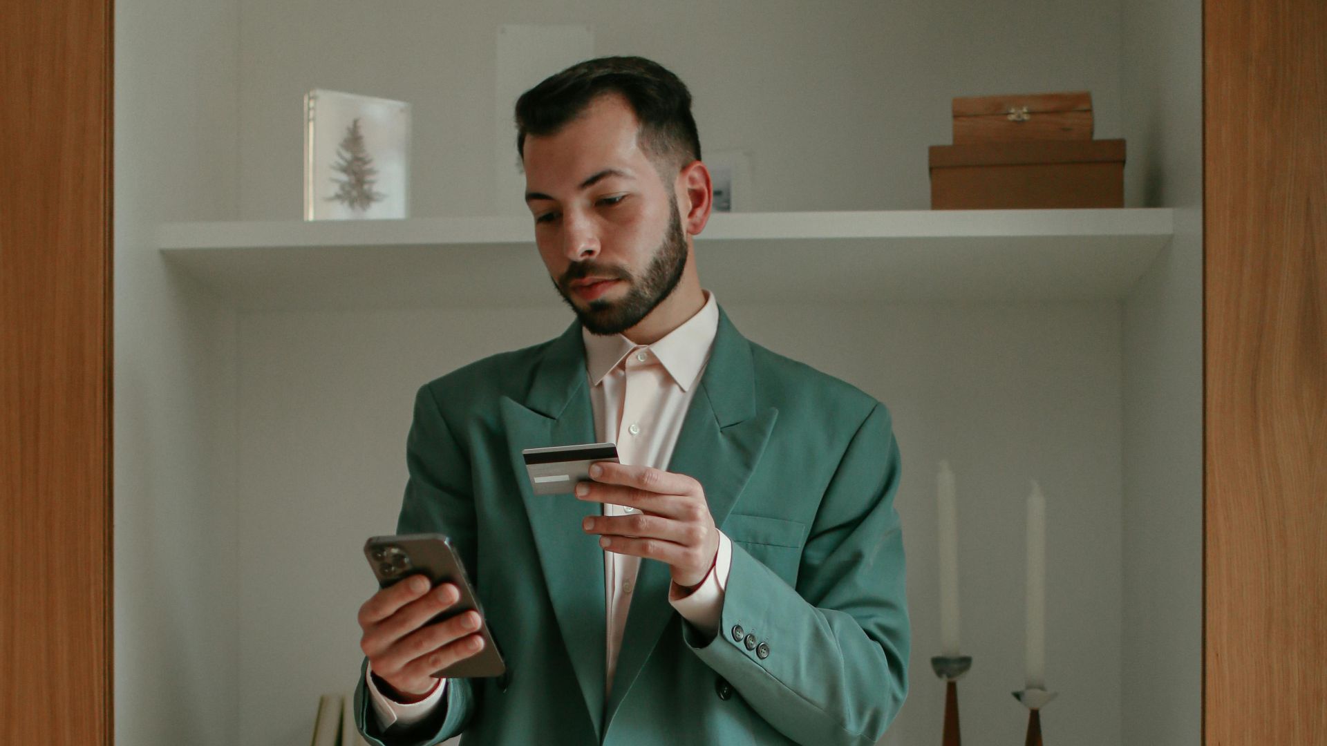 Barefoot man using smartphone and credit card for online shopping indoors. Modern lifestyle concept.