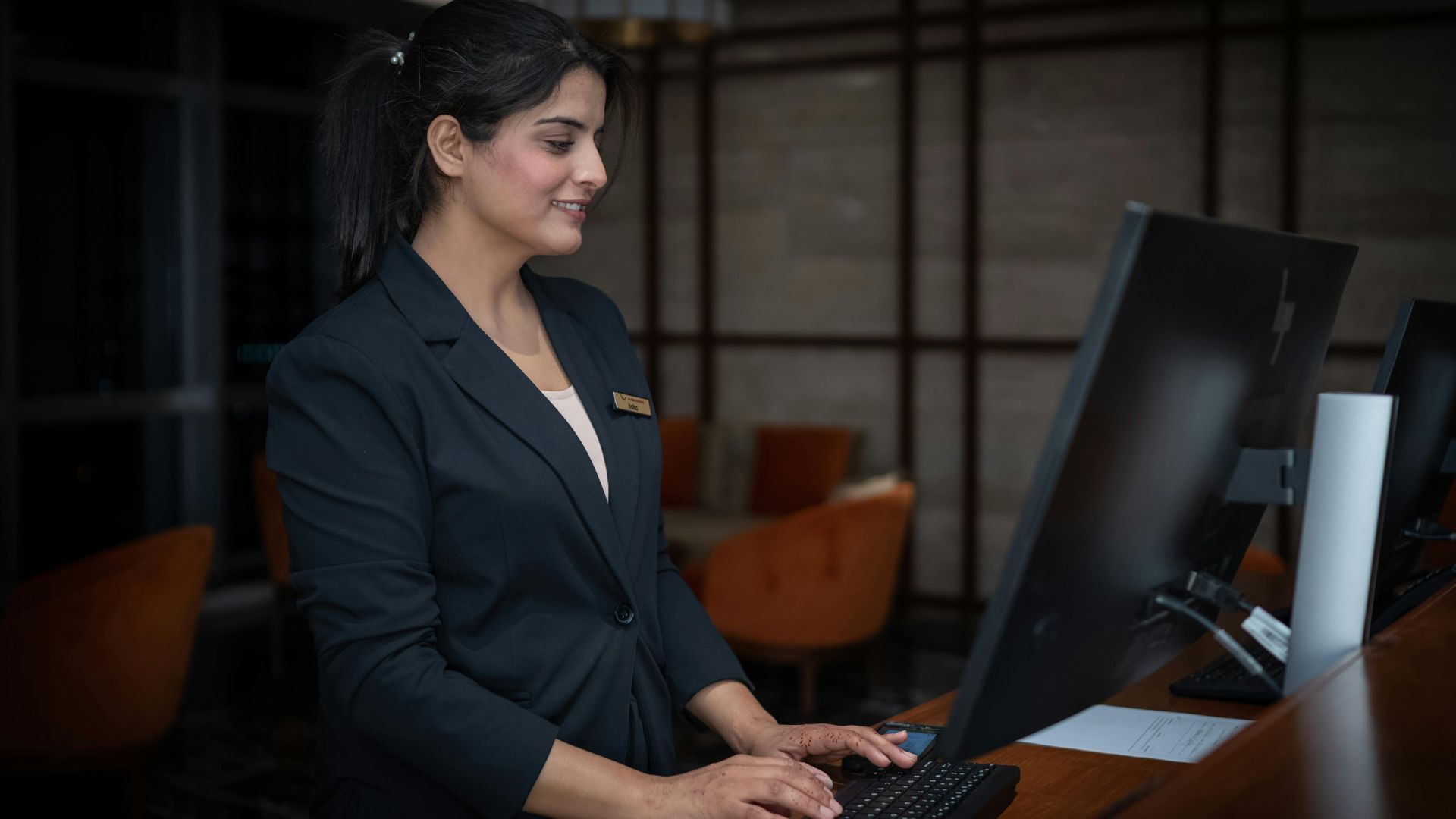A female receptionist working at a hotel front desk in Islamabad, Pakistan.