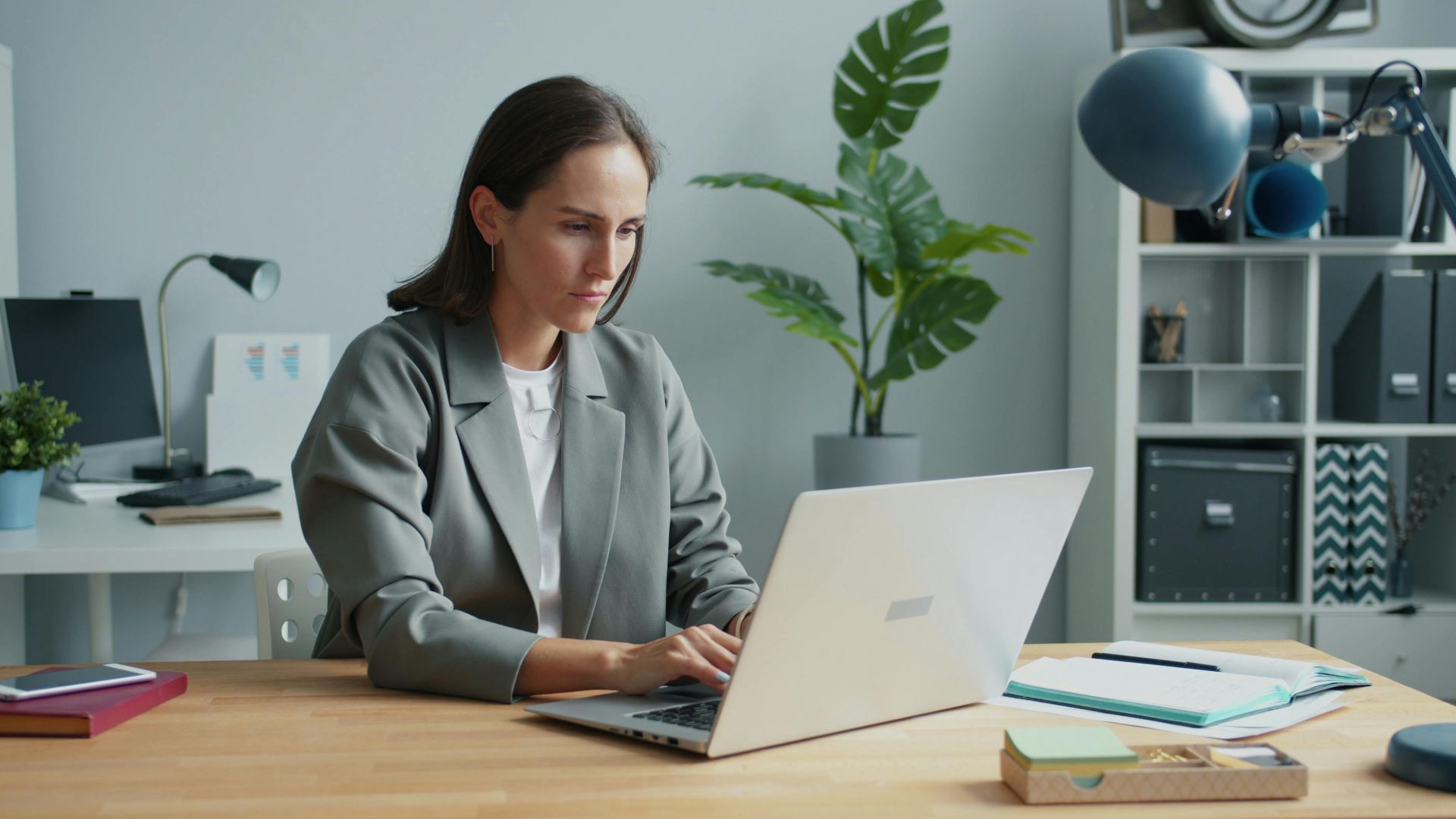Businesswoman focused on laptop in modern home office setting.