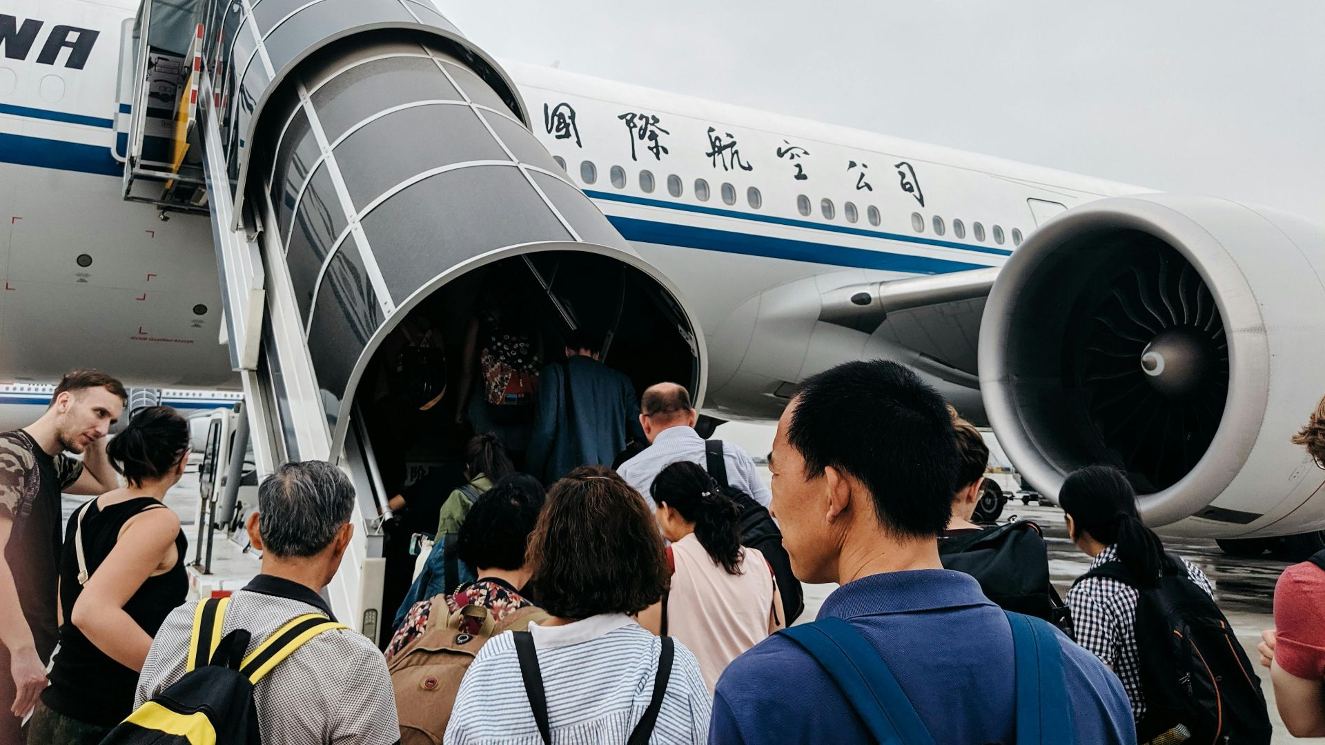 A group of people boarding an airplane via a jet bridge at Beijing Airport, China.
