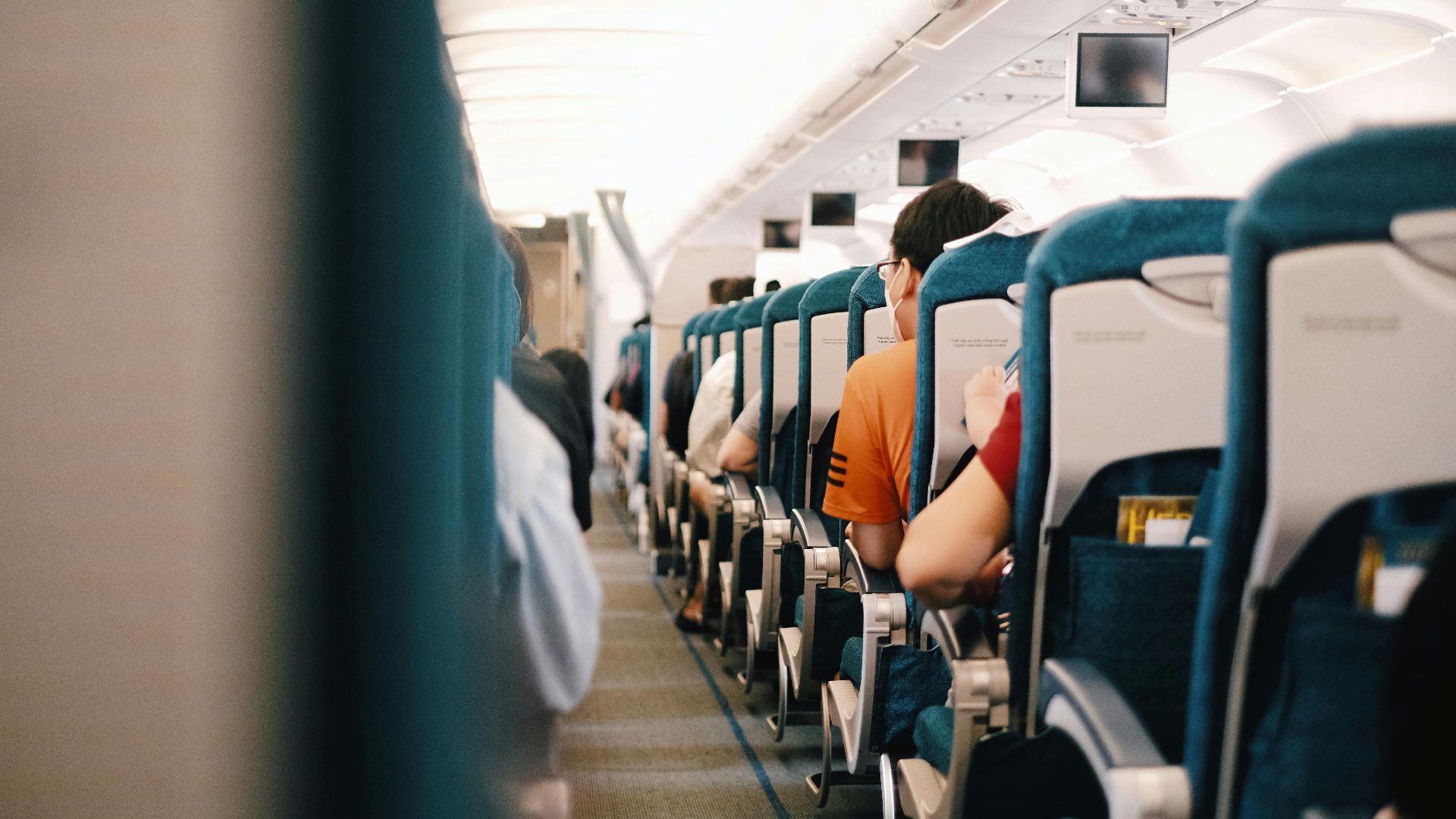 Interior view of airplane cabin showing passengers seated during a flight.