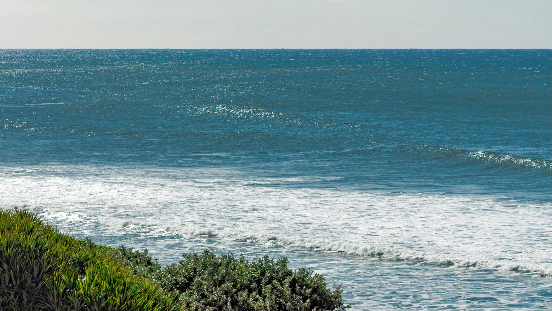 A peaceful seascape with rolling waves under clear blue skies, capturing coastal tranquility.