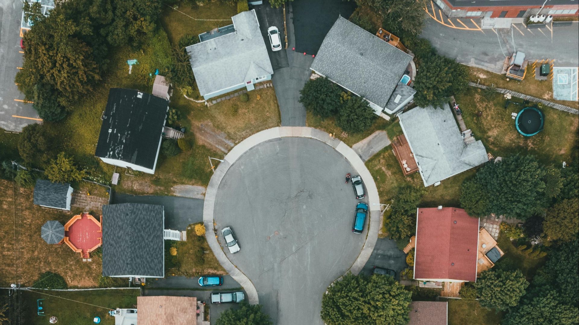 High angle aerial shot of a suburban cul-de-sac surrounded by houses, trees, and streets.