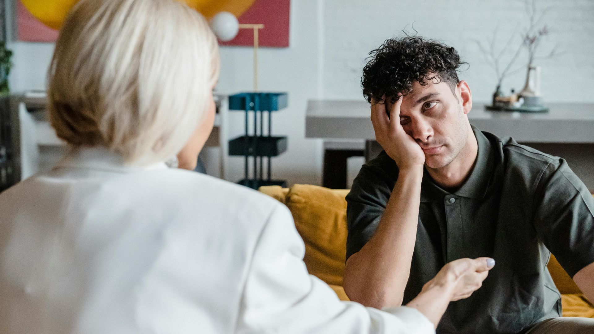 A therapist in session with a young man in a modern, artistic office setting.