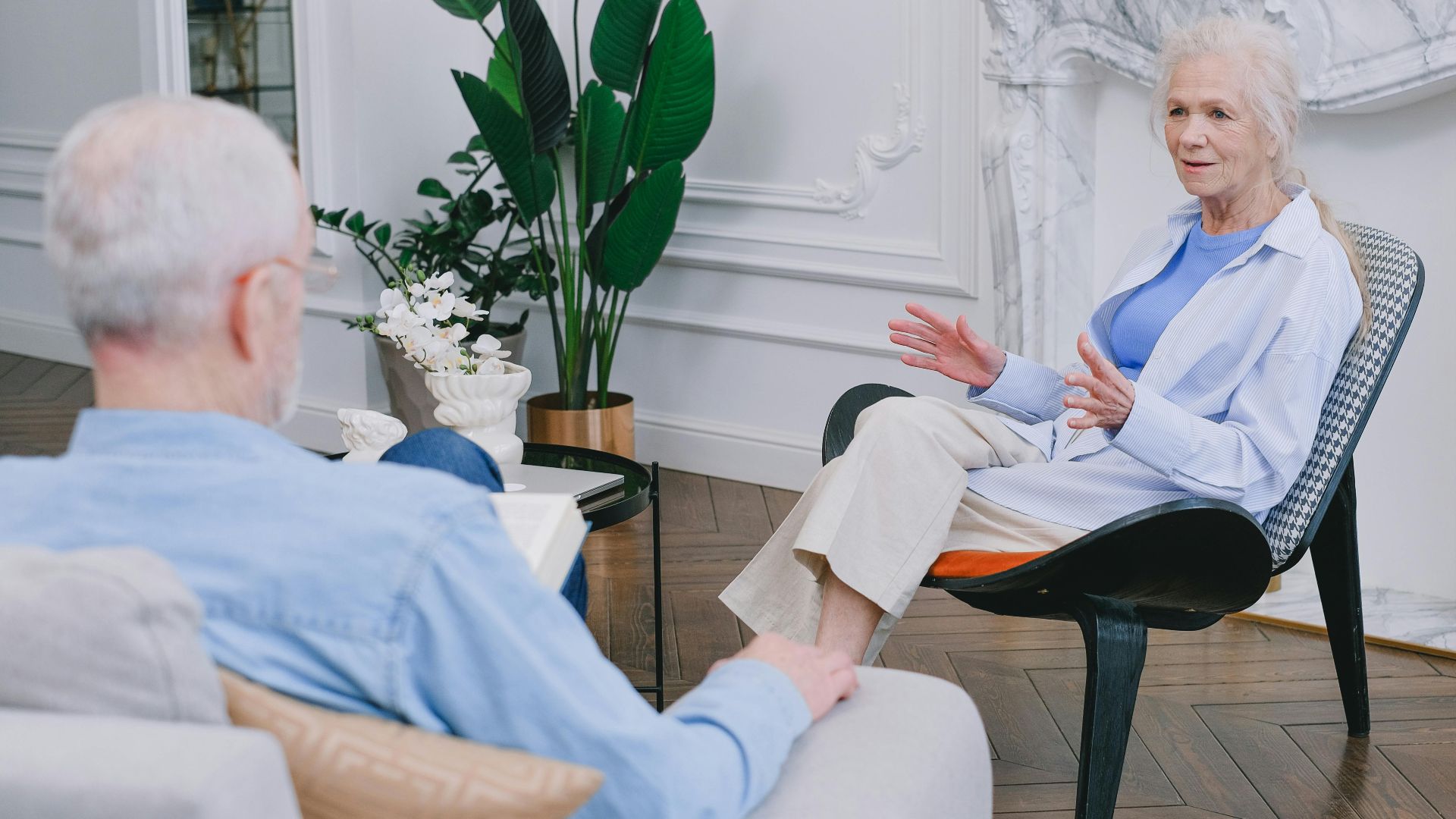 Elderly couple discussing in a stylish living room with plants.