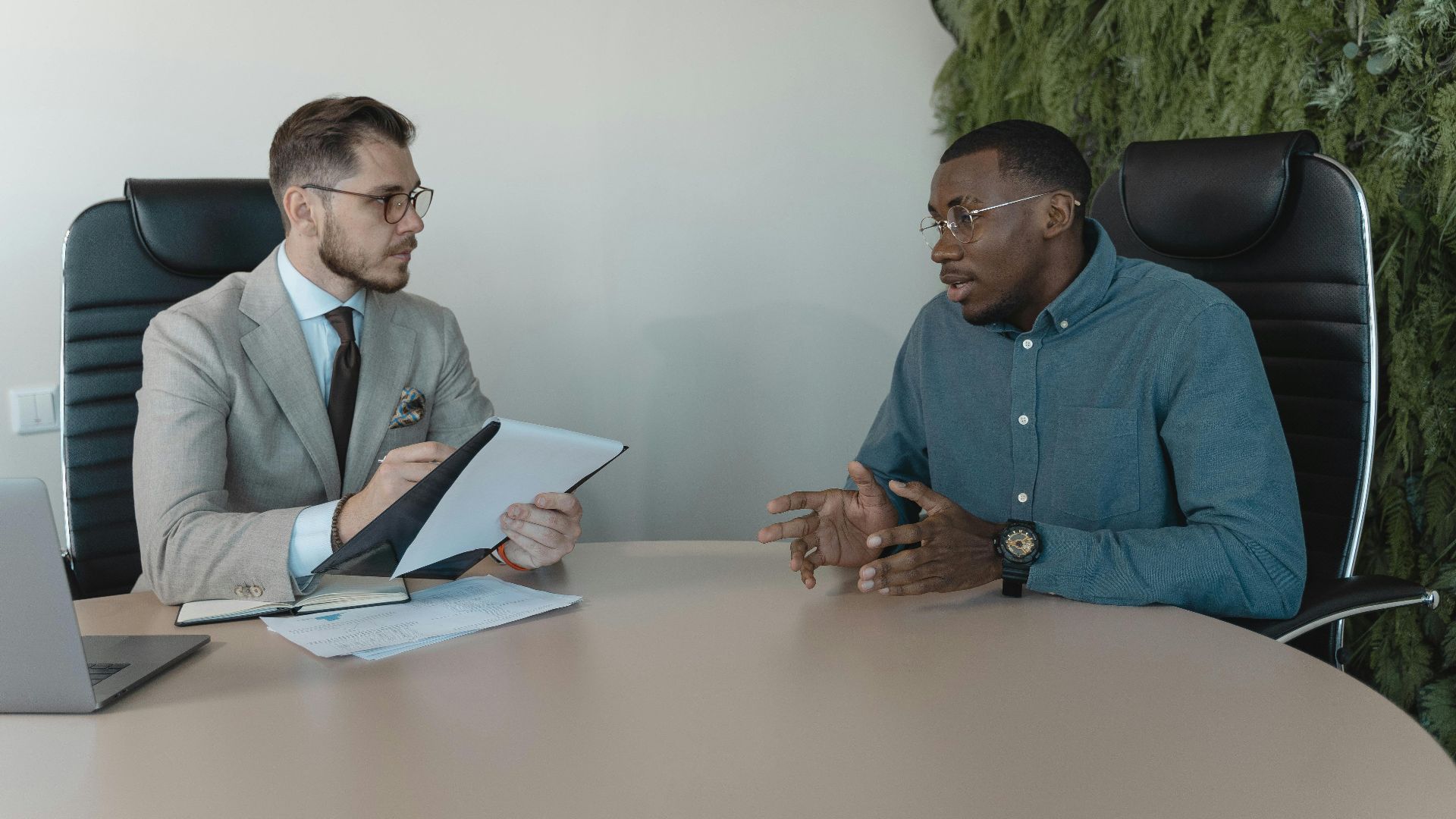 Two businessmen engaged in a discussion during a job interview in a contemporary office environment.