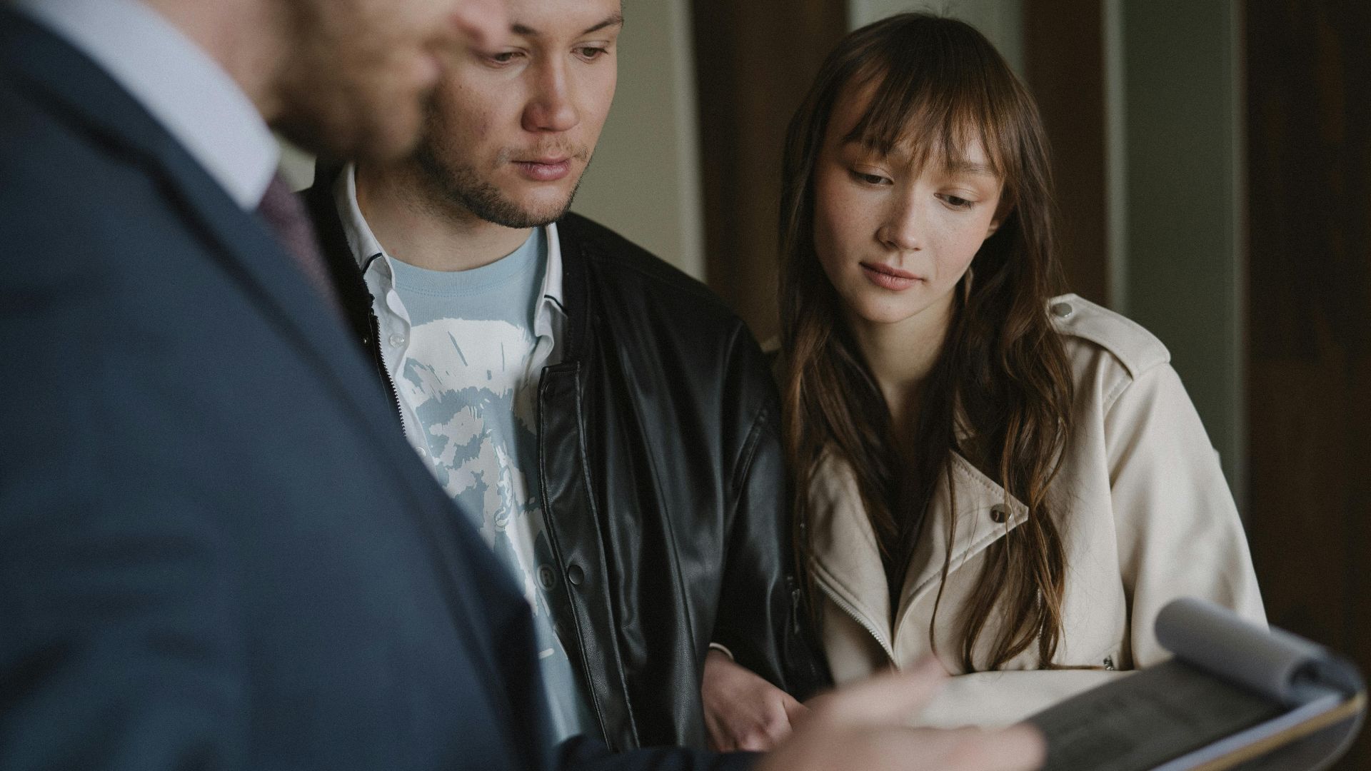 A couple discusses home buying details with a realtor inside a modern apartment.