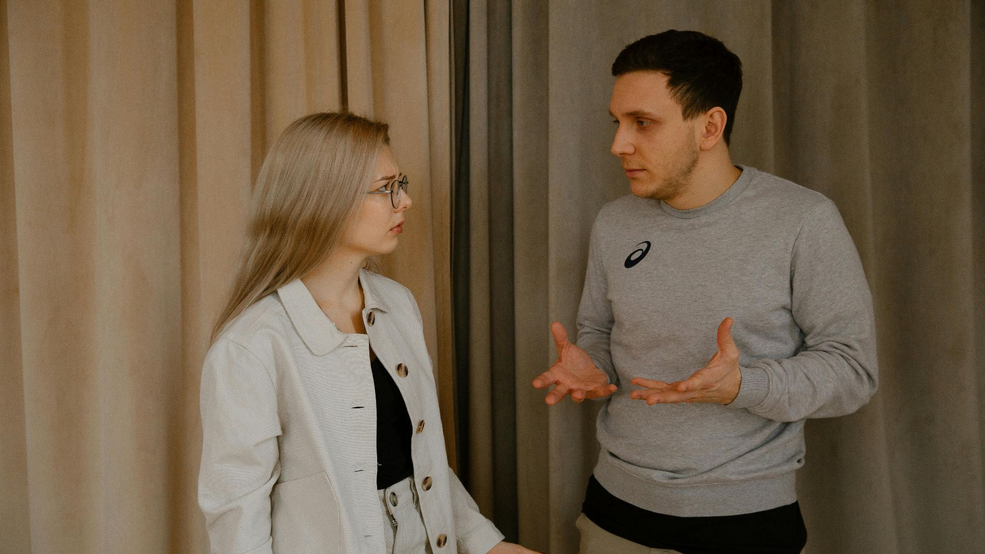 A young couple passionately discussing indoors, capturing intense emotions and gestures.