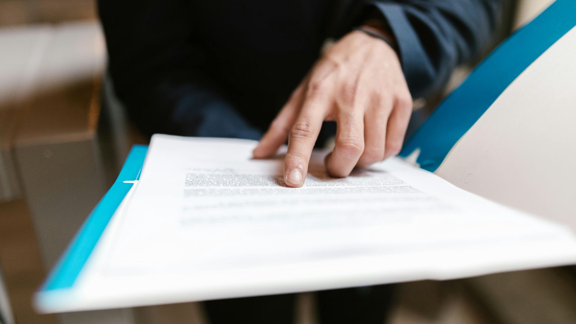 Close-up of a hand pointing at text on a business document in an office environment.