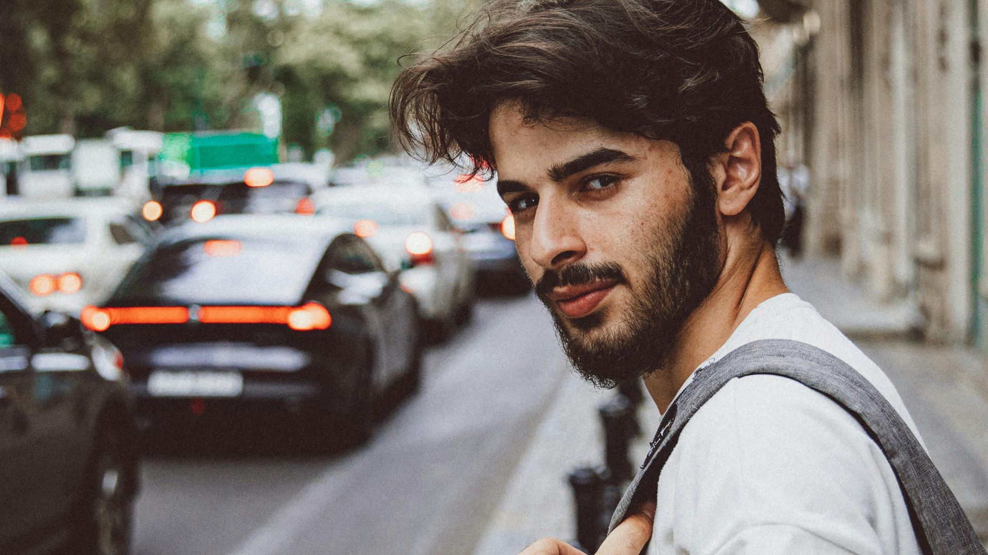 Stylish young man walking along a busy street in Baku, Azerbaijan with cars and architecture in the background.