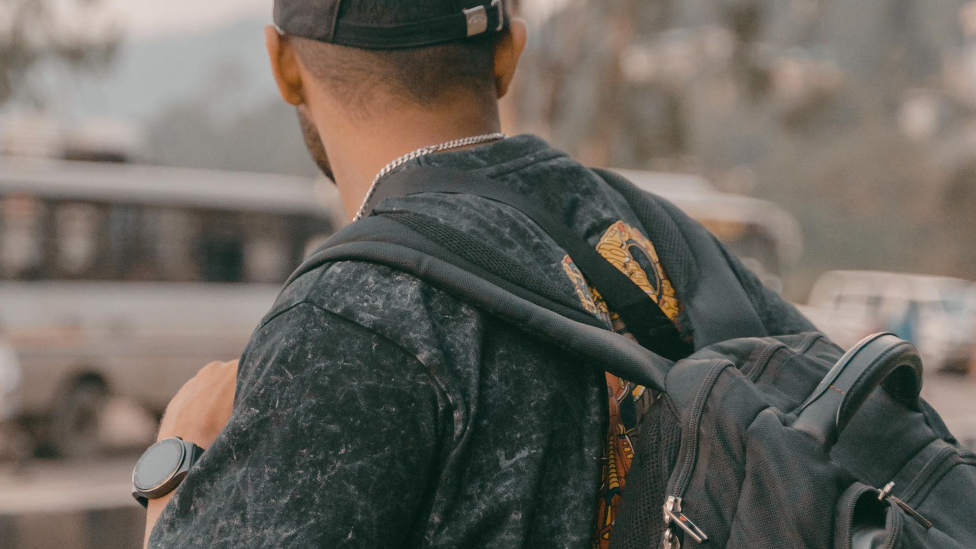 Traveler wearing backpack and baseball cap standing on road, outdoors.
