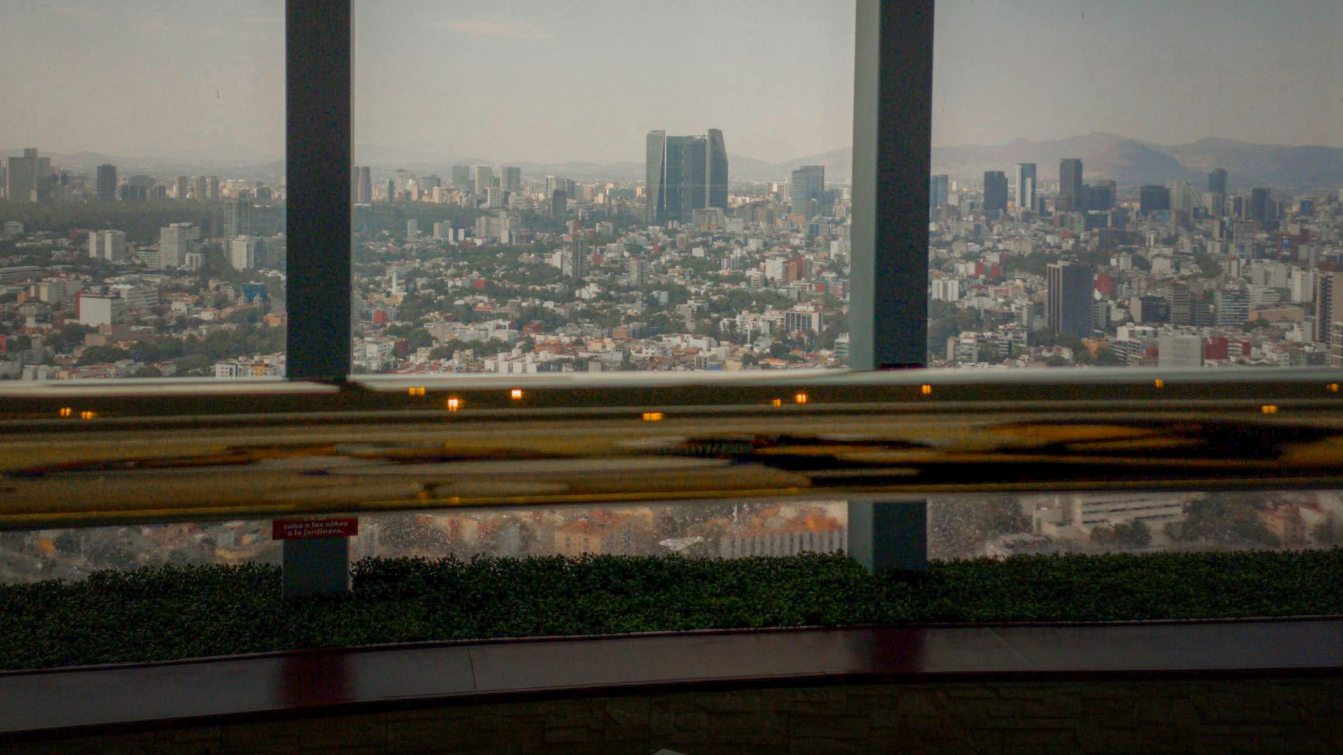 Breathtaking view of Mexico City skyscrapers through large windows under a clear sky.