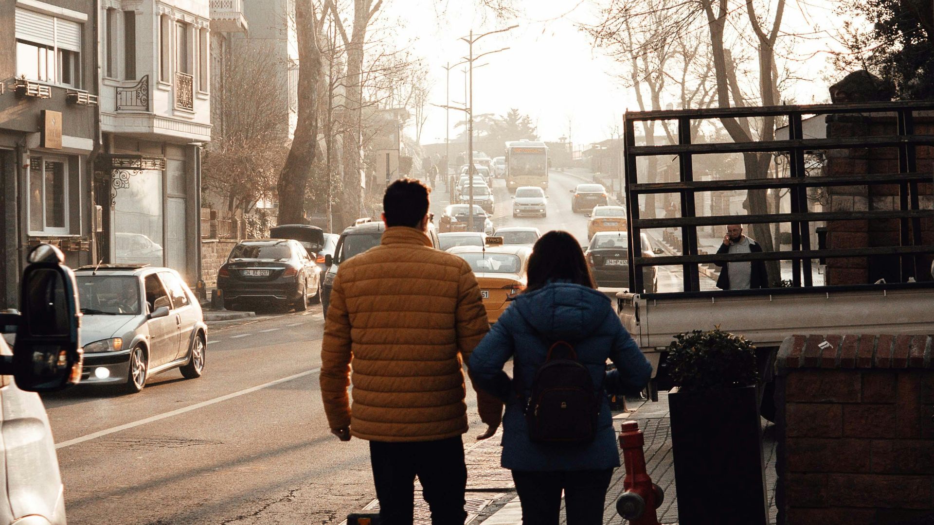 Back view of people in casual clothes walking on pavement near old building in city