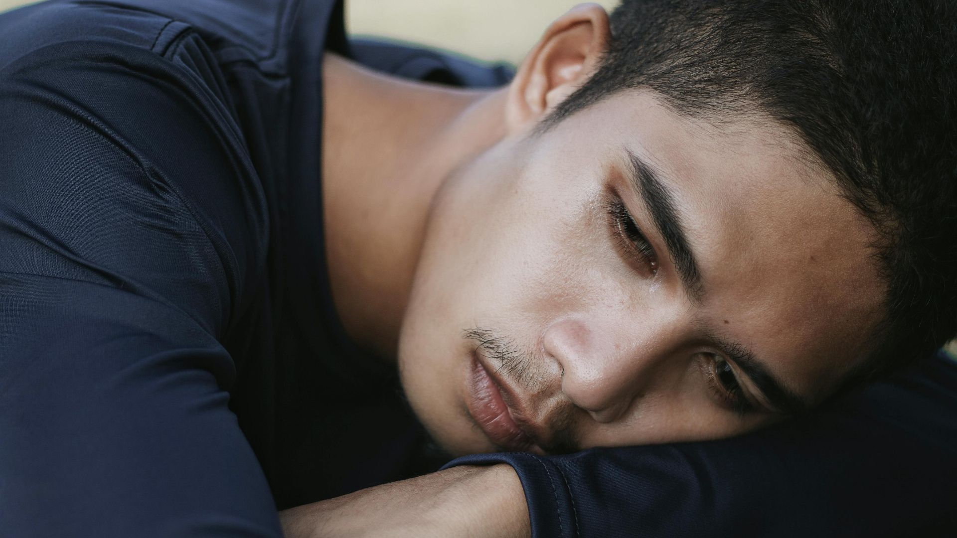 Close-up portrait of a young man expressing deep emotional introspection.