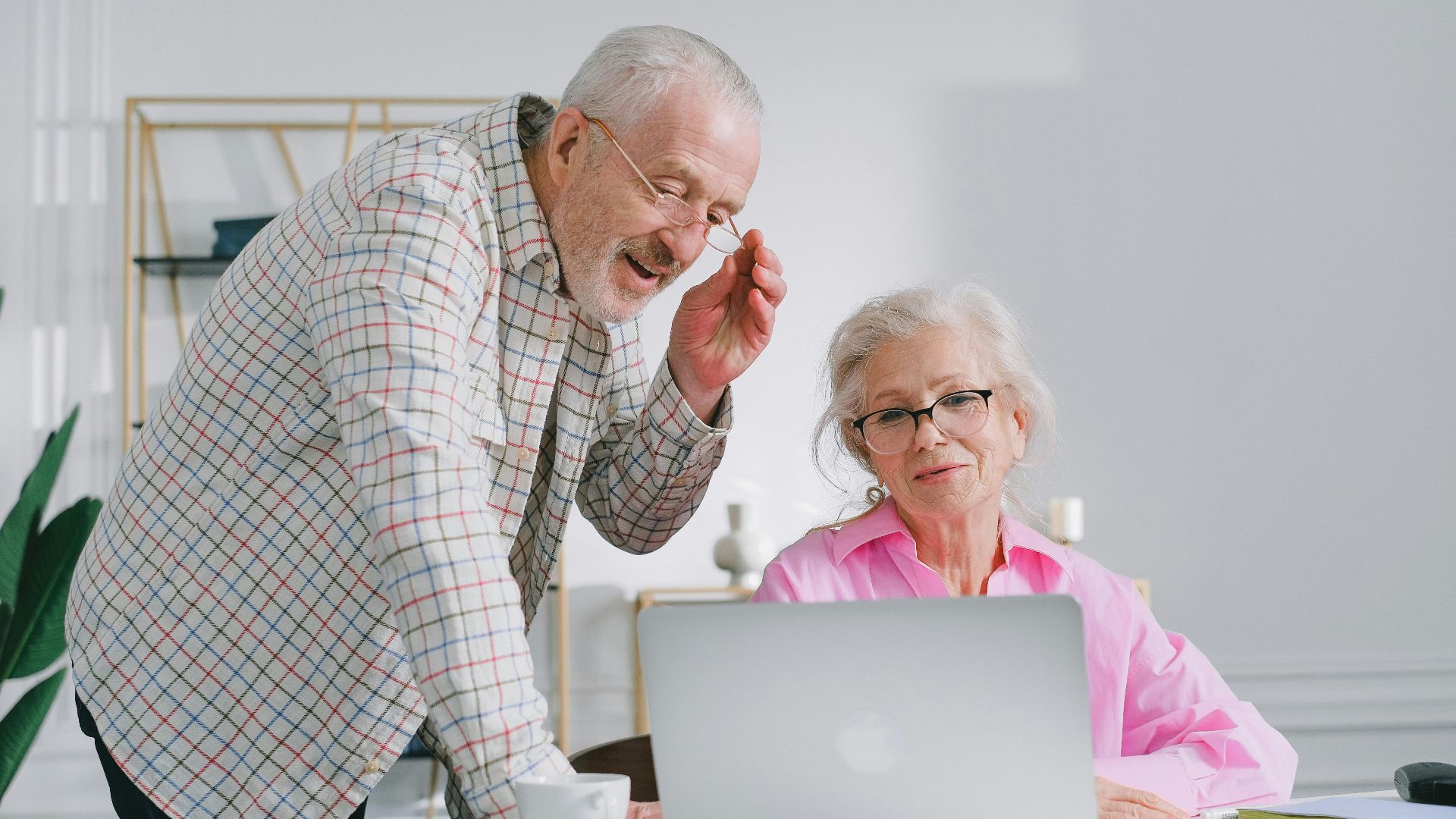 Senior couple enjoying a conversation while using a laptop indoors, showcasing active lifestyle.