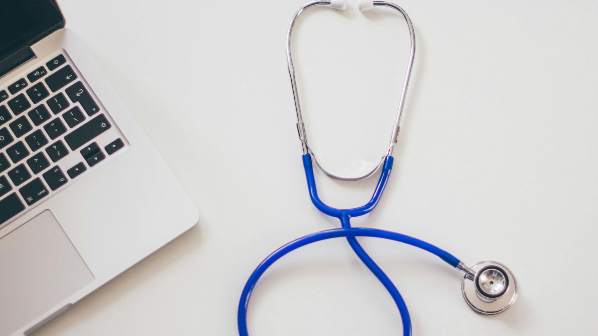 Medical stethoscope and laptop on a white desk, symbolizing digital health solutions.