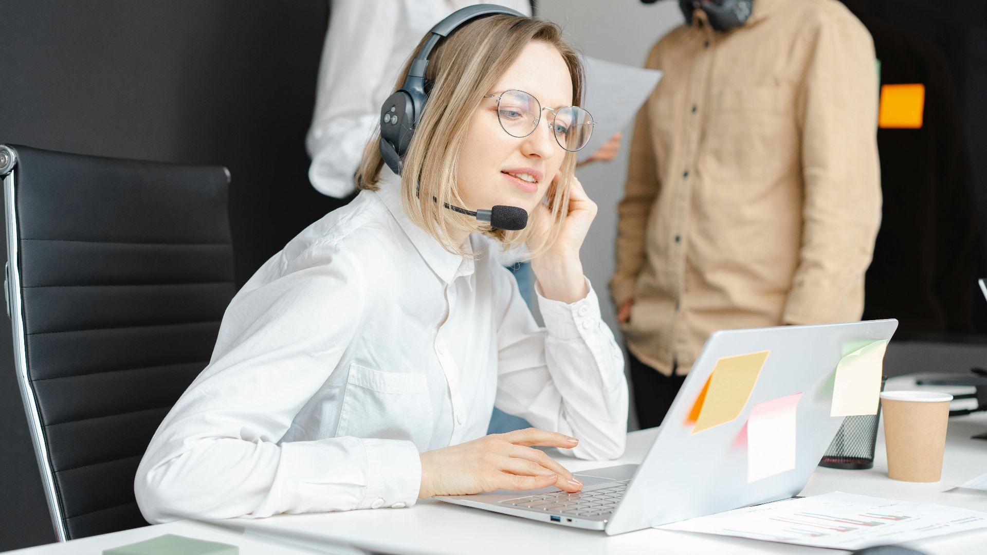 Customer support professionals working with headsets and laptops in a modern office environment.