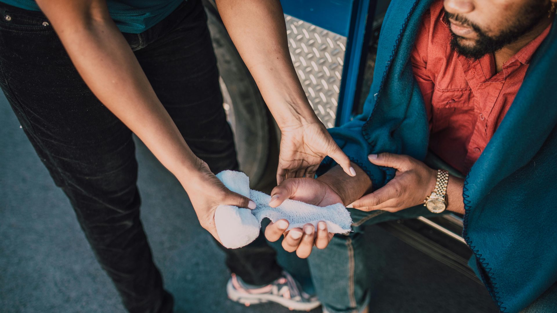 Close-up of a person applying gauze to an injured hand, highlighting first aid care.