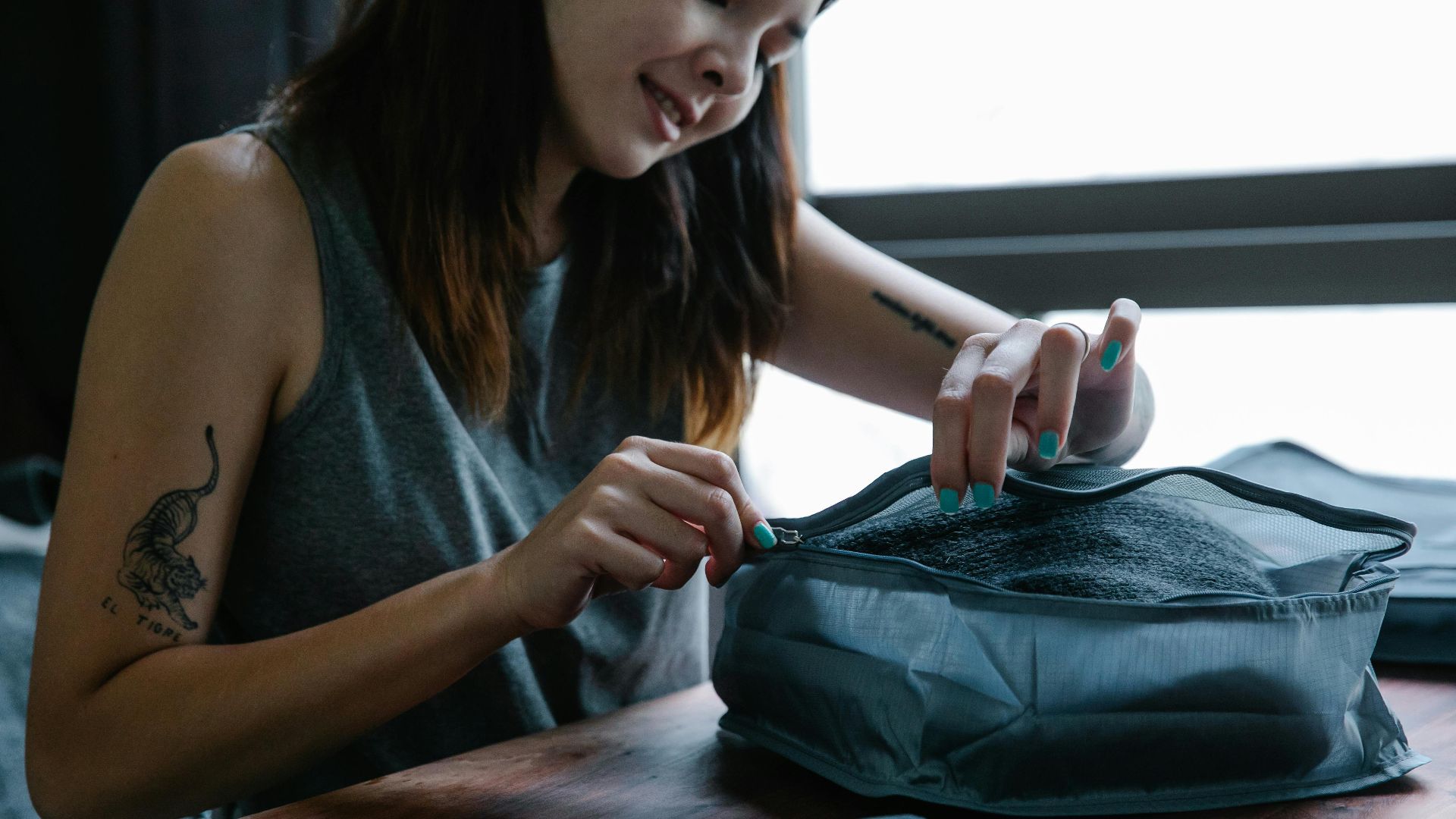 Woman smiling as she zips a travel organizer indoors, preparing for a trip.