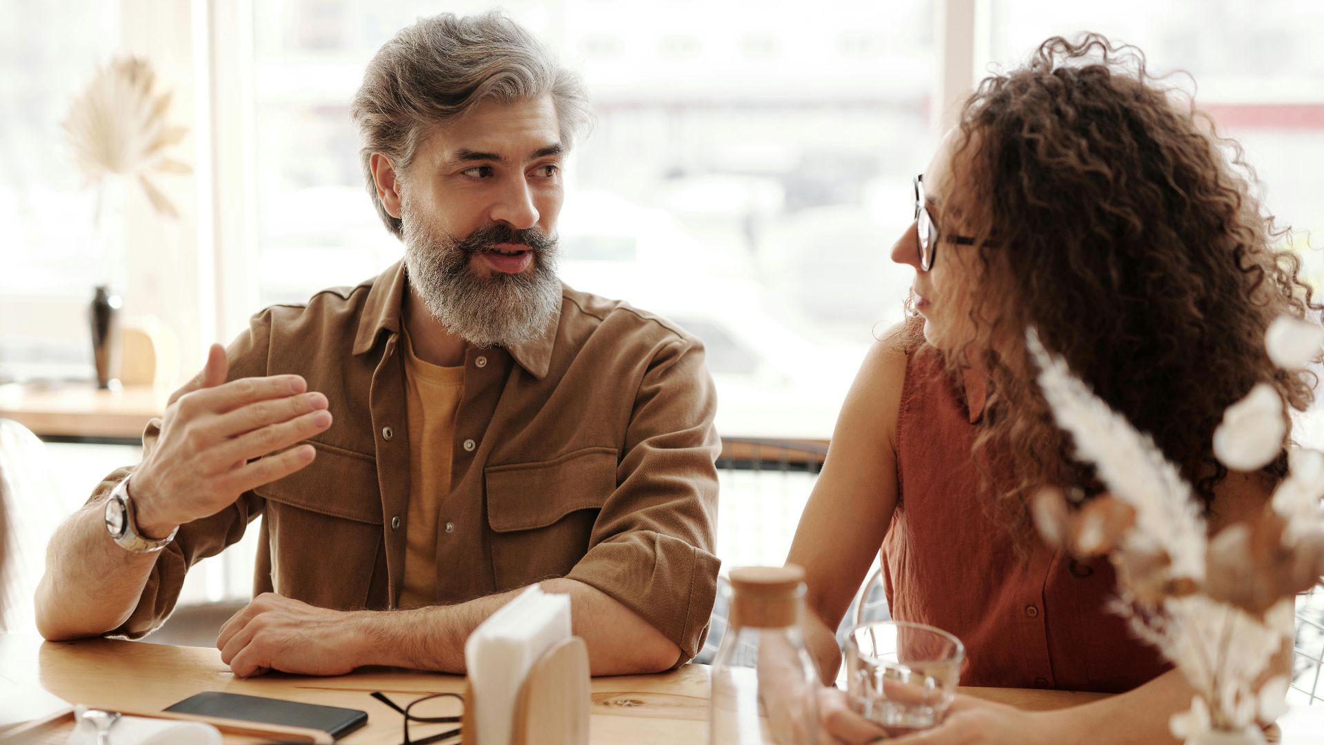 A friendly discussion among colleagues in a cozy cafe environment, fostering teamwork and collaboration.